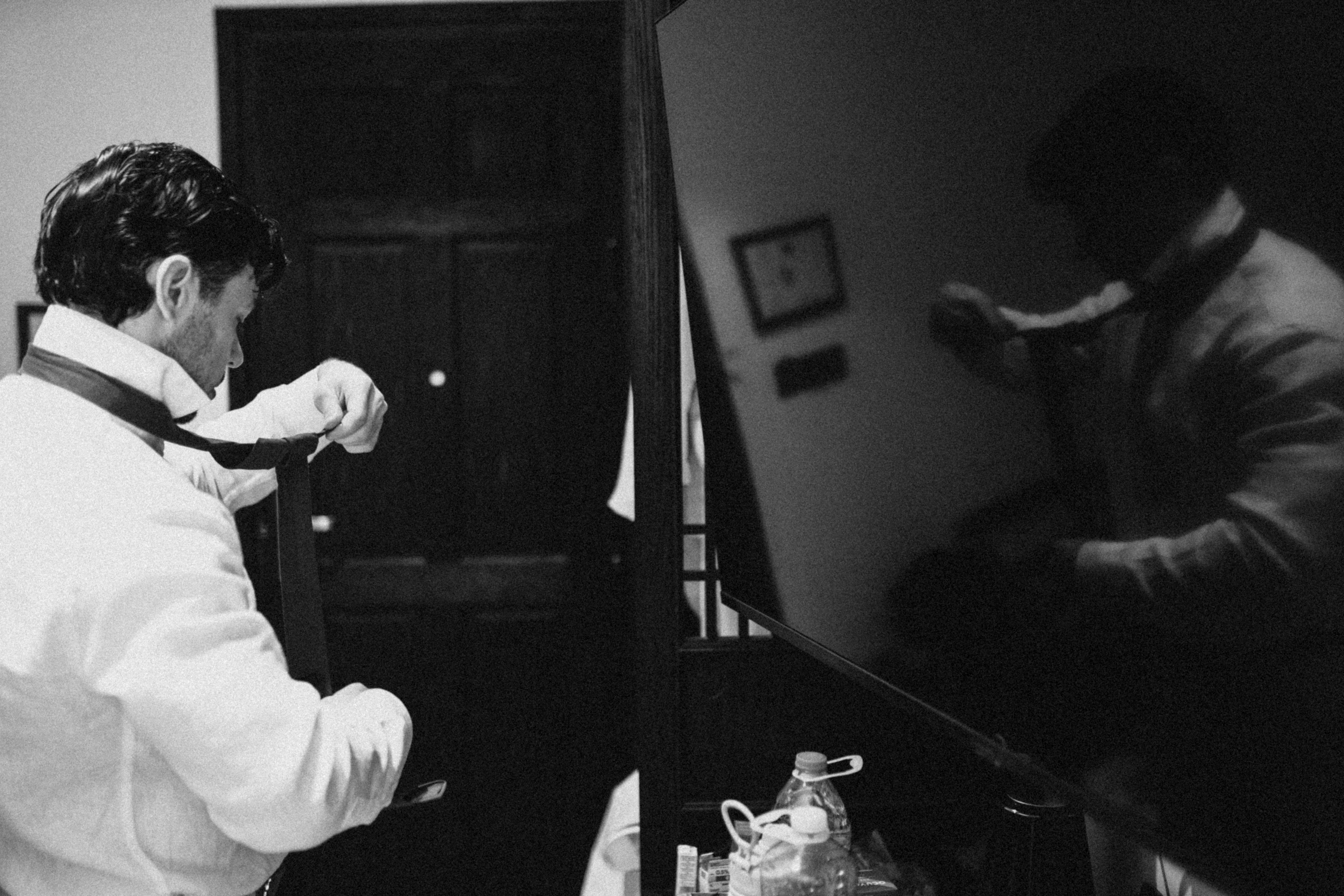 Man tying his tie in front of a mirror