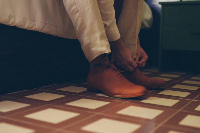 Tying the laces on elegant brown leather shoes, preparing for an Adelaide rendezvous.