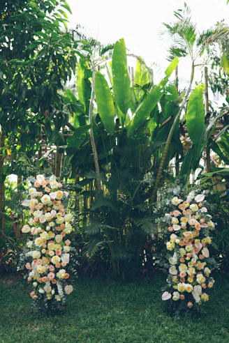 Two floral arrangements flank large tropical plants