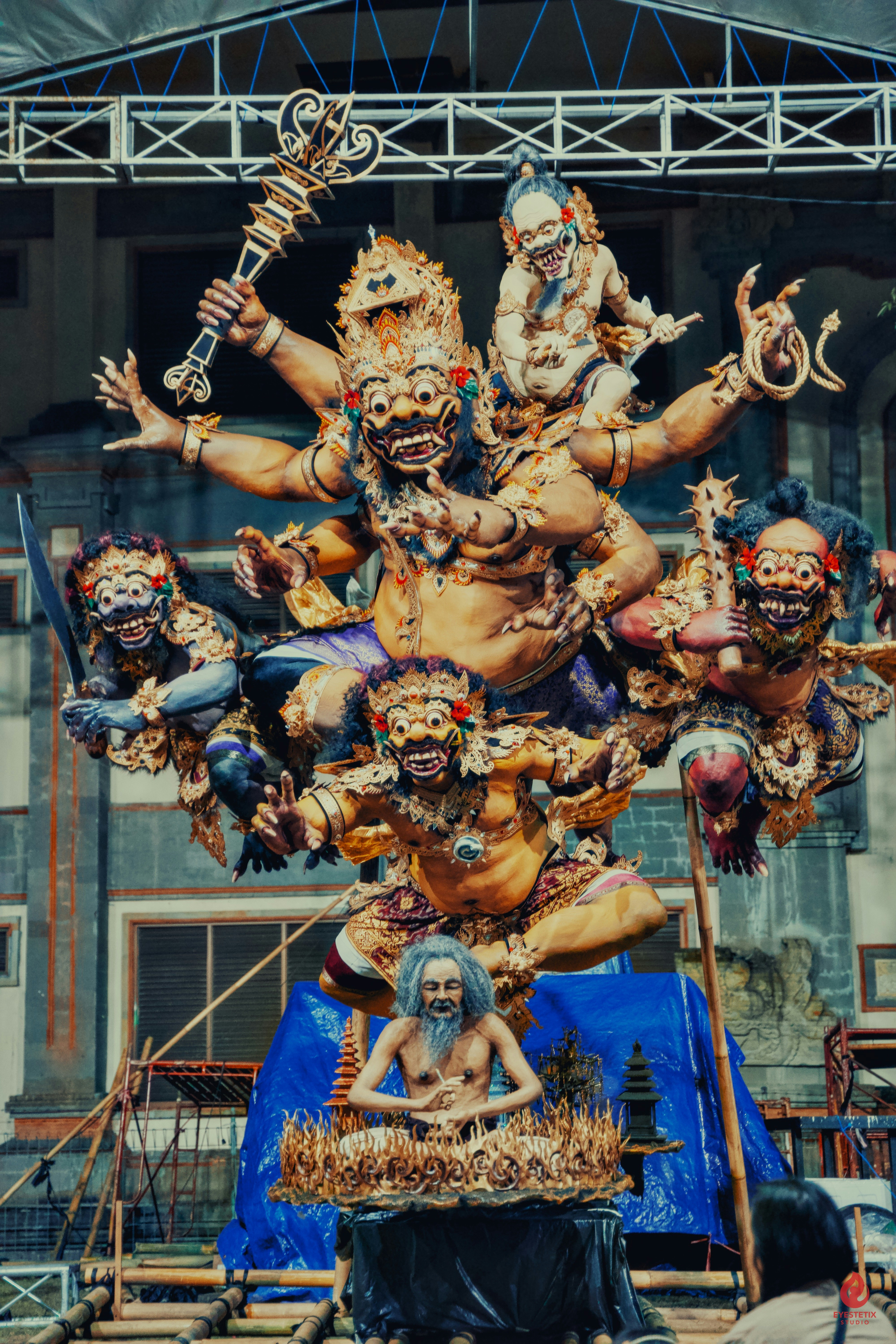 Intricate balinese statue of a multi-armed deity and figures.