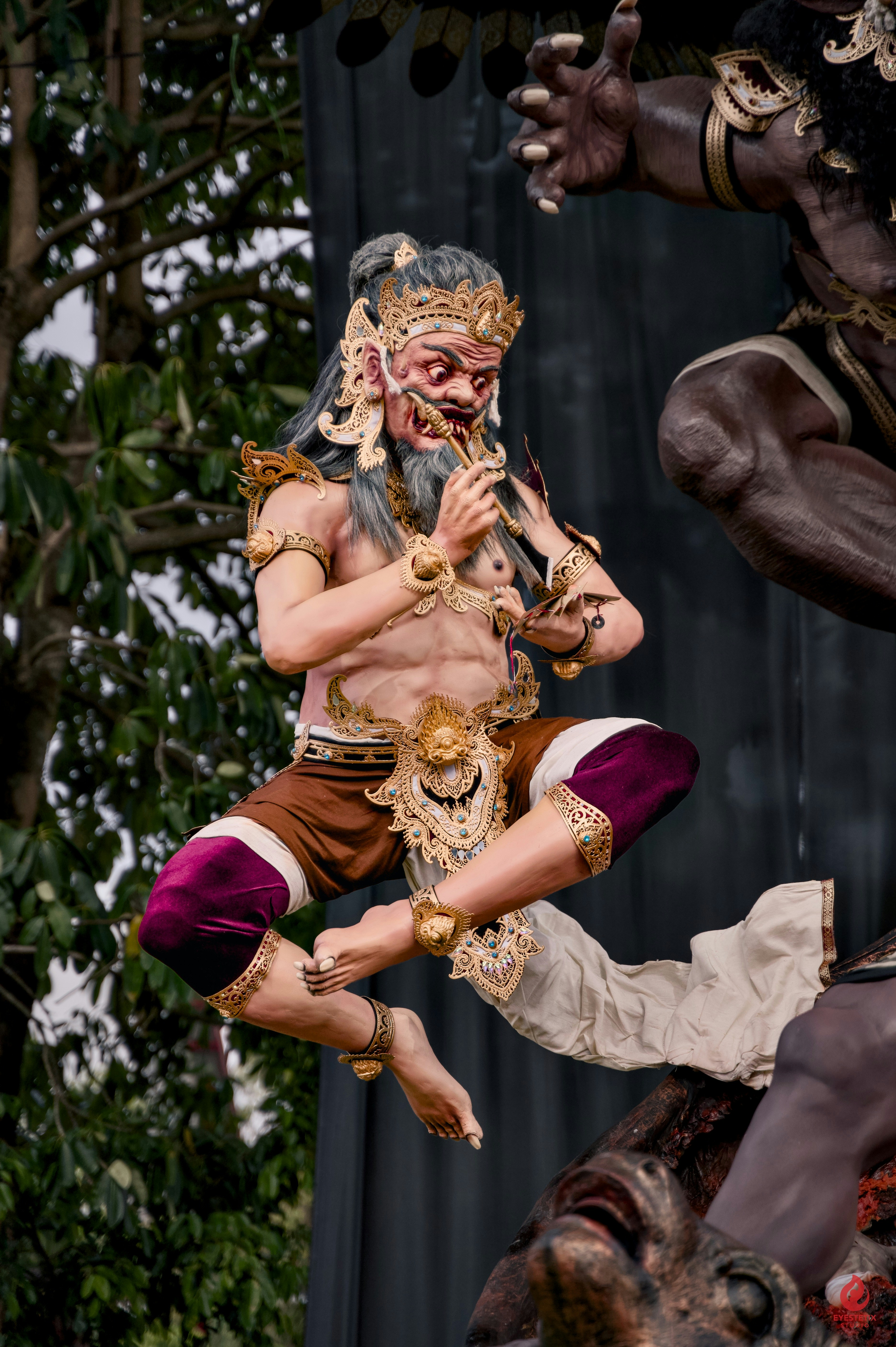 A demon figure in traditional costume leaps mid-air.