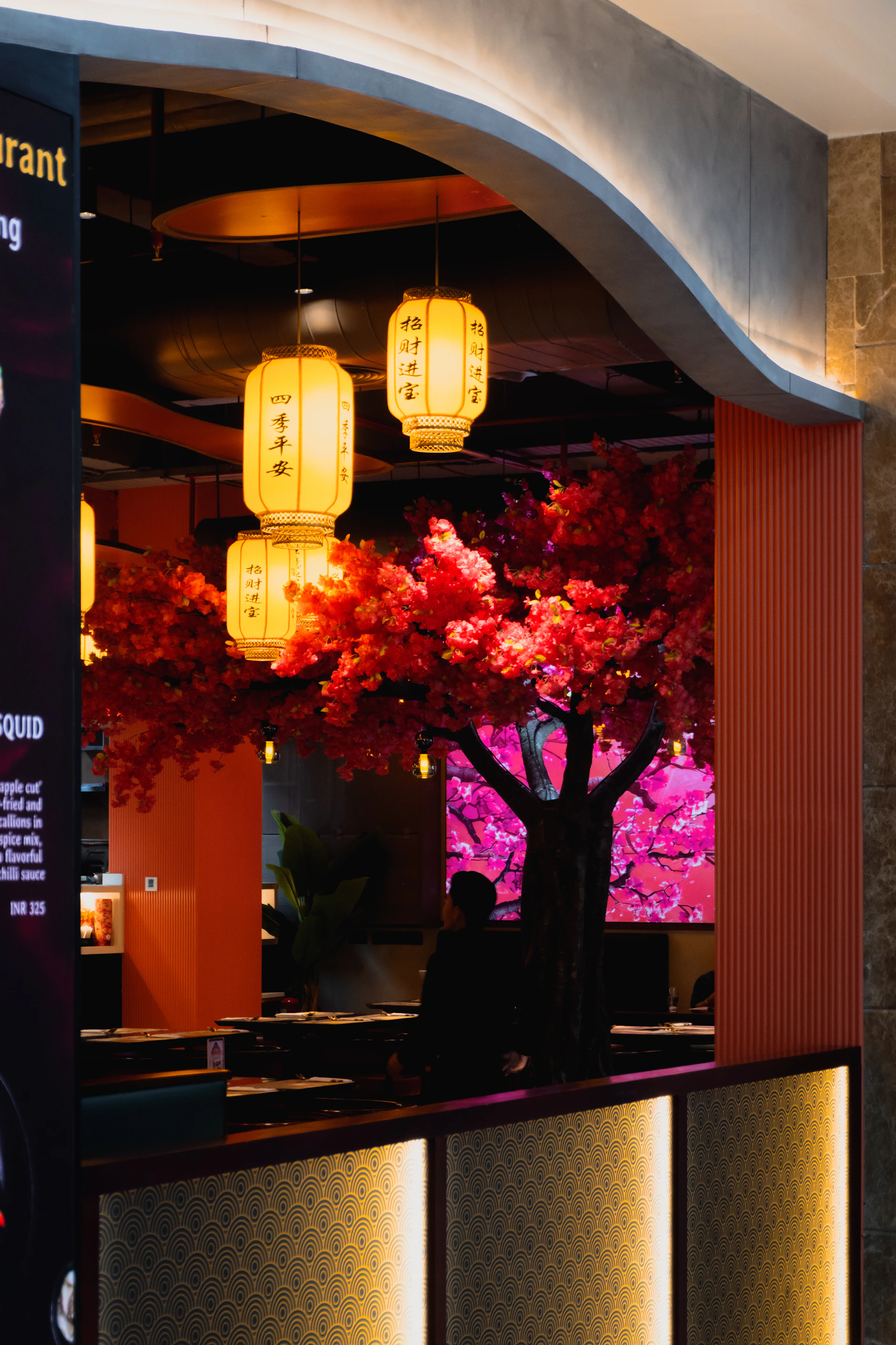 A restaurant interior with decorative trees and lanterns