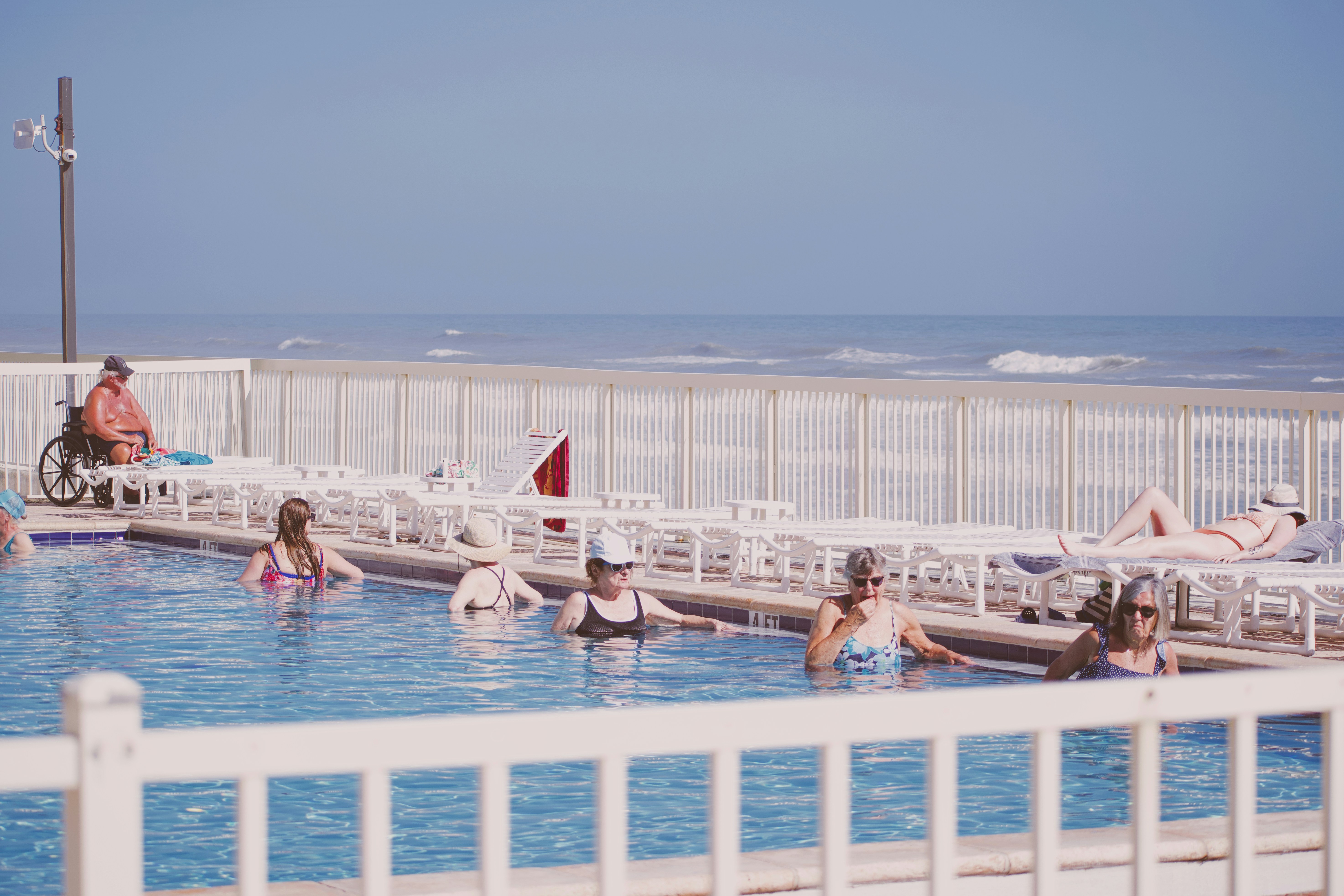 People relaxing in a swimming pool by the ocean.