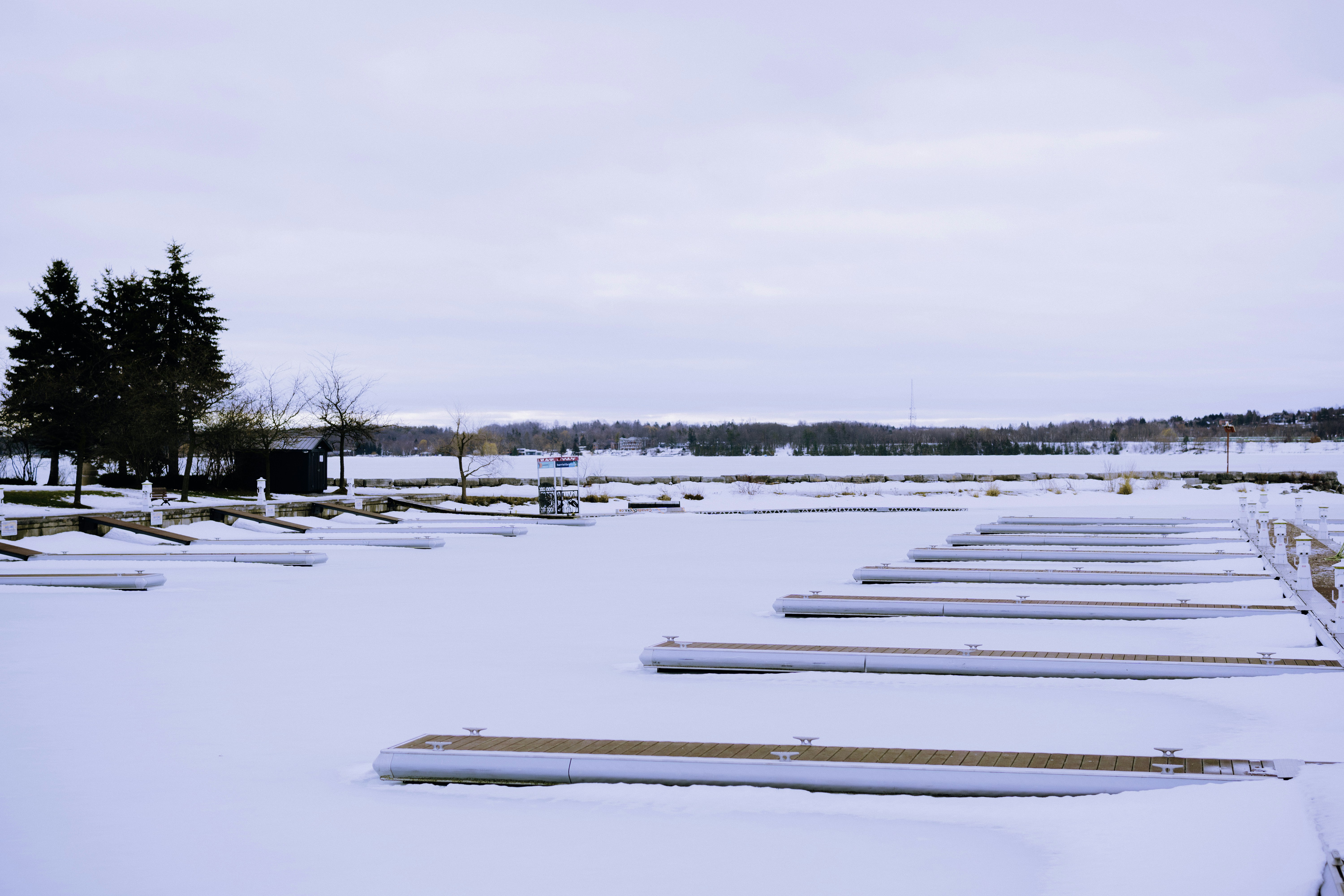 Empty marina docks covered in snow under a cloudy sky