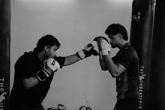 Two men boxing in a gym with punching bags.
