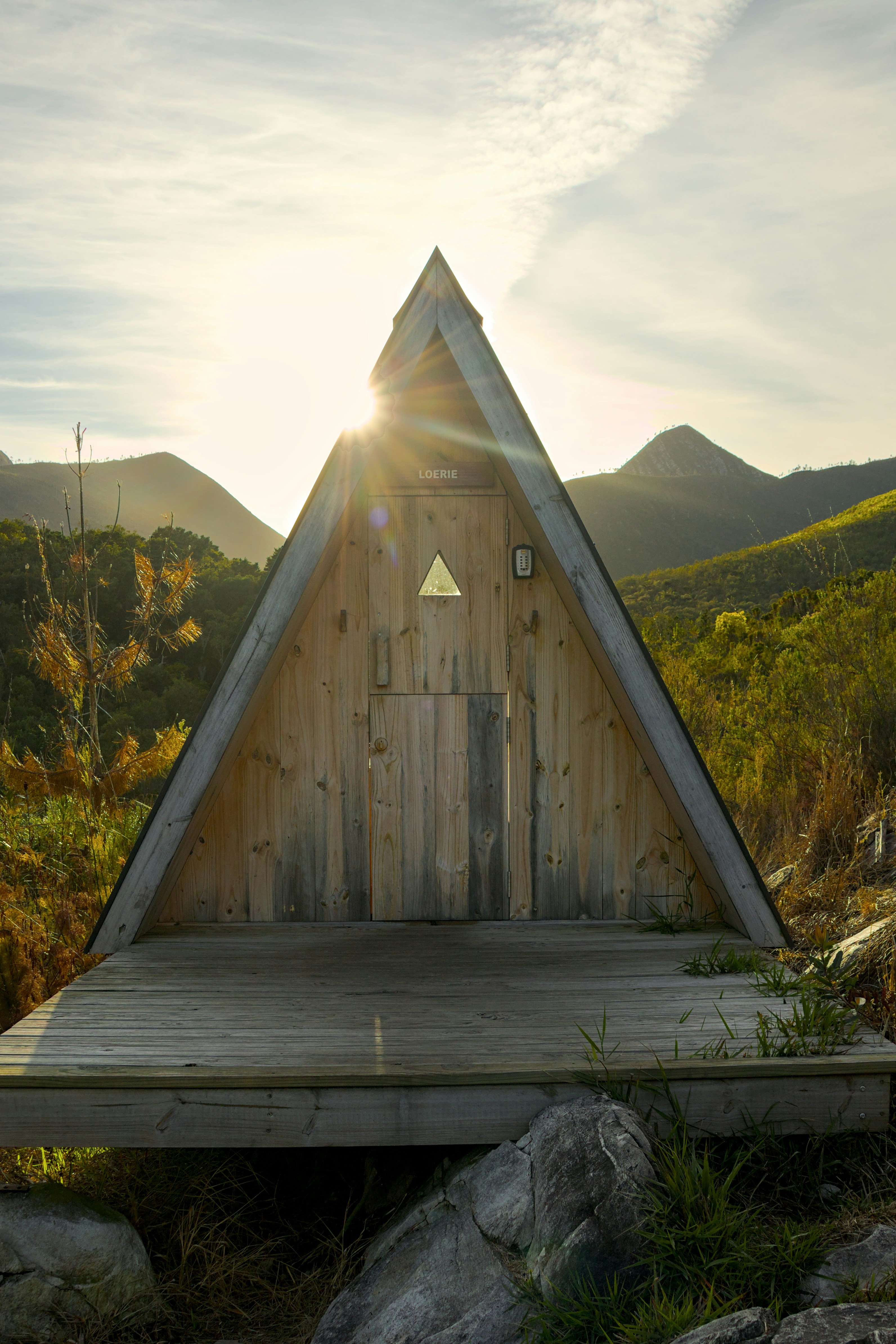 Wooden triangular cabin in a sunny mountain landscape