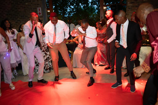 People dancing on a red carpet at a party.