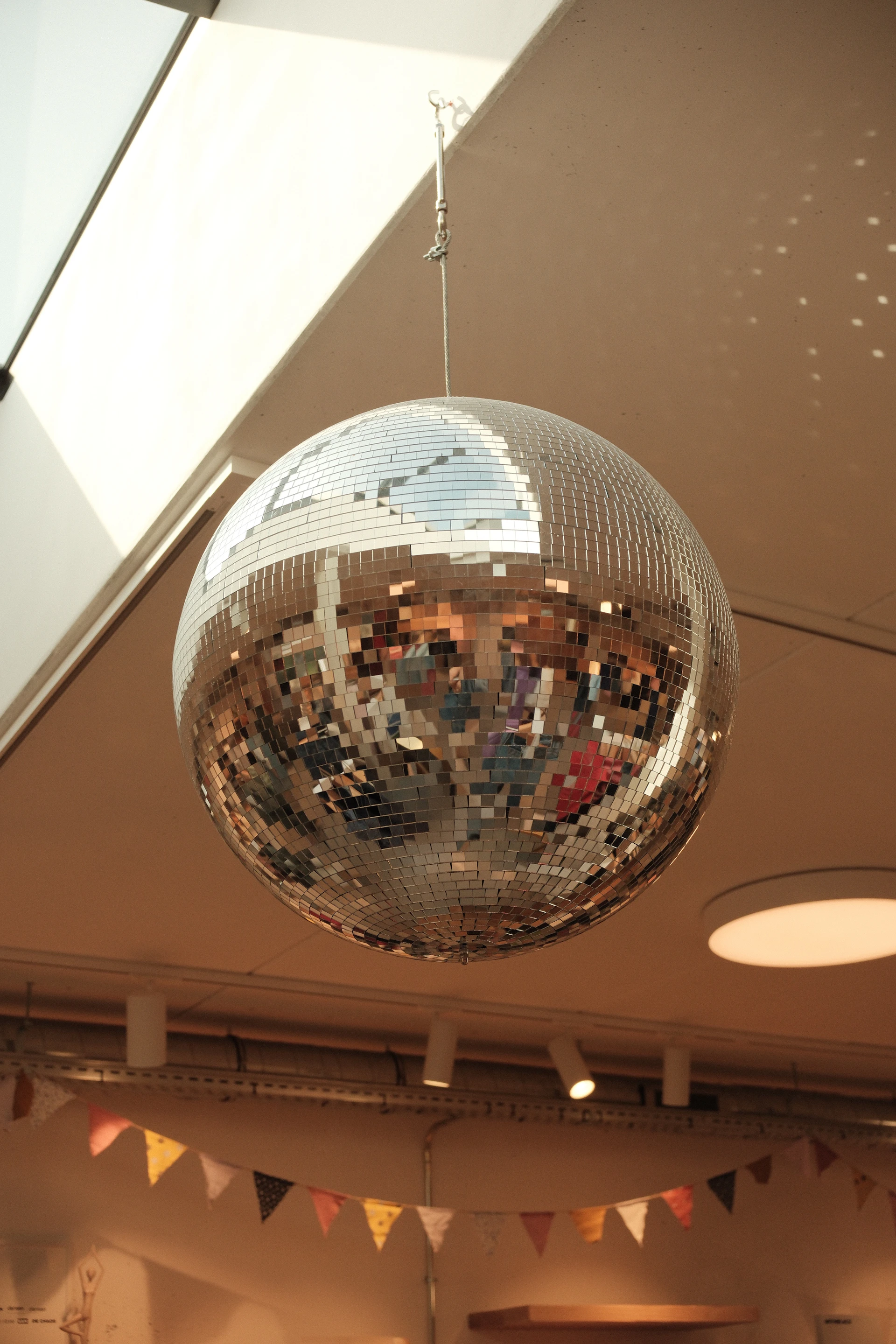 A disco ball hangs from the ceiling with colorful flags.