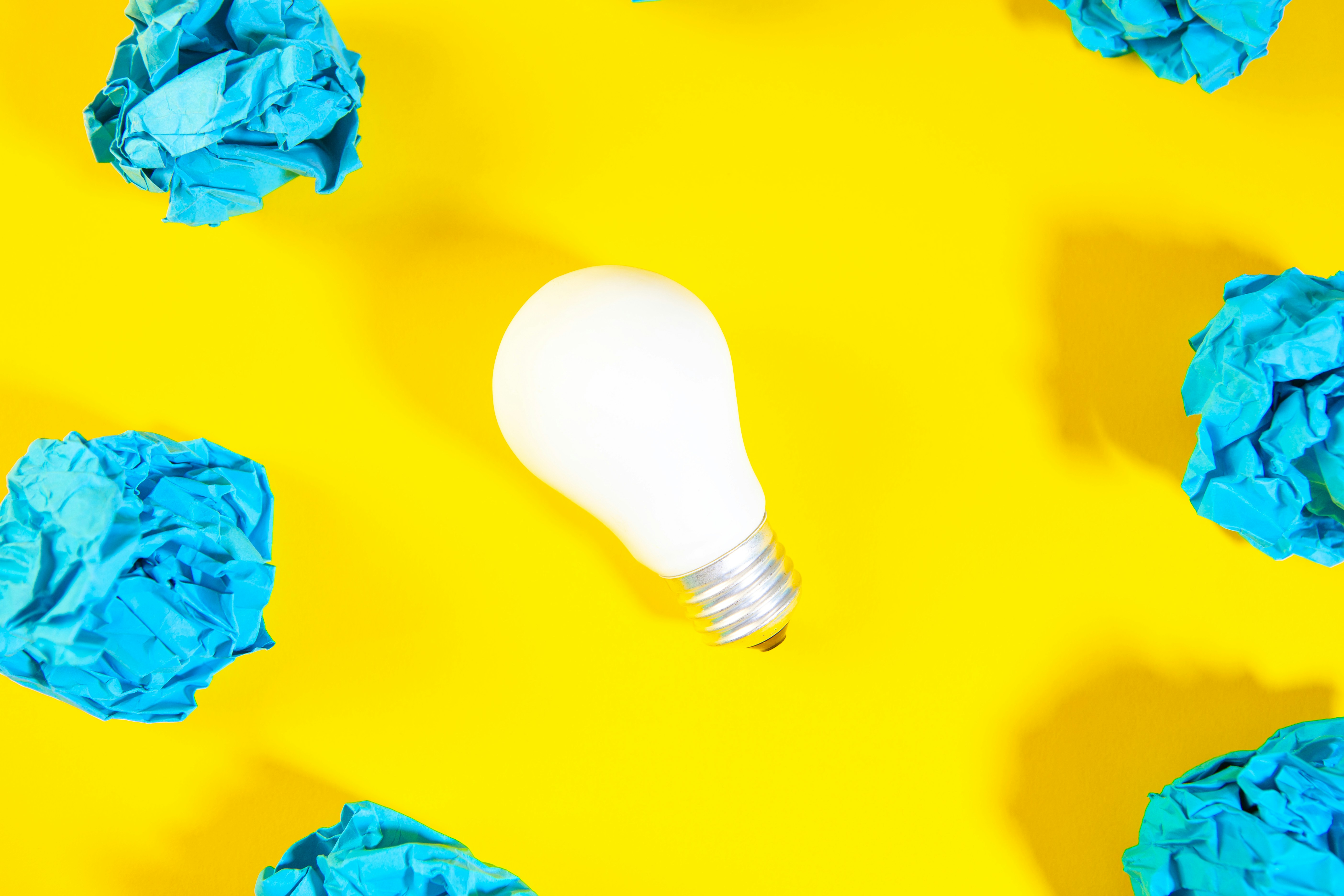 A white light bulb surrounded by crumpled blue paper.