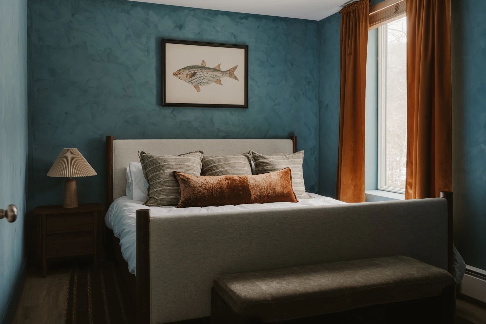 A painted bedroom with a deep-blue feature wall and cream trim.
