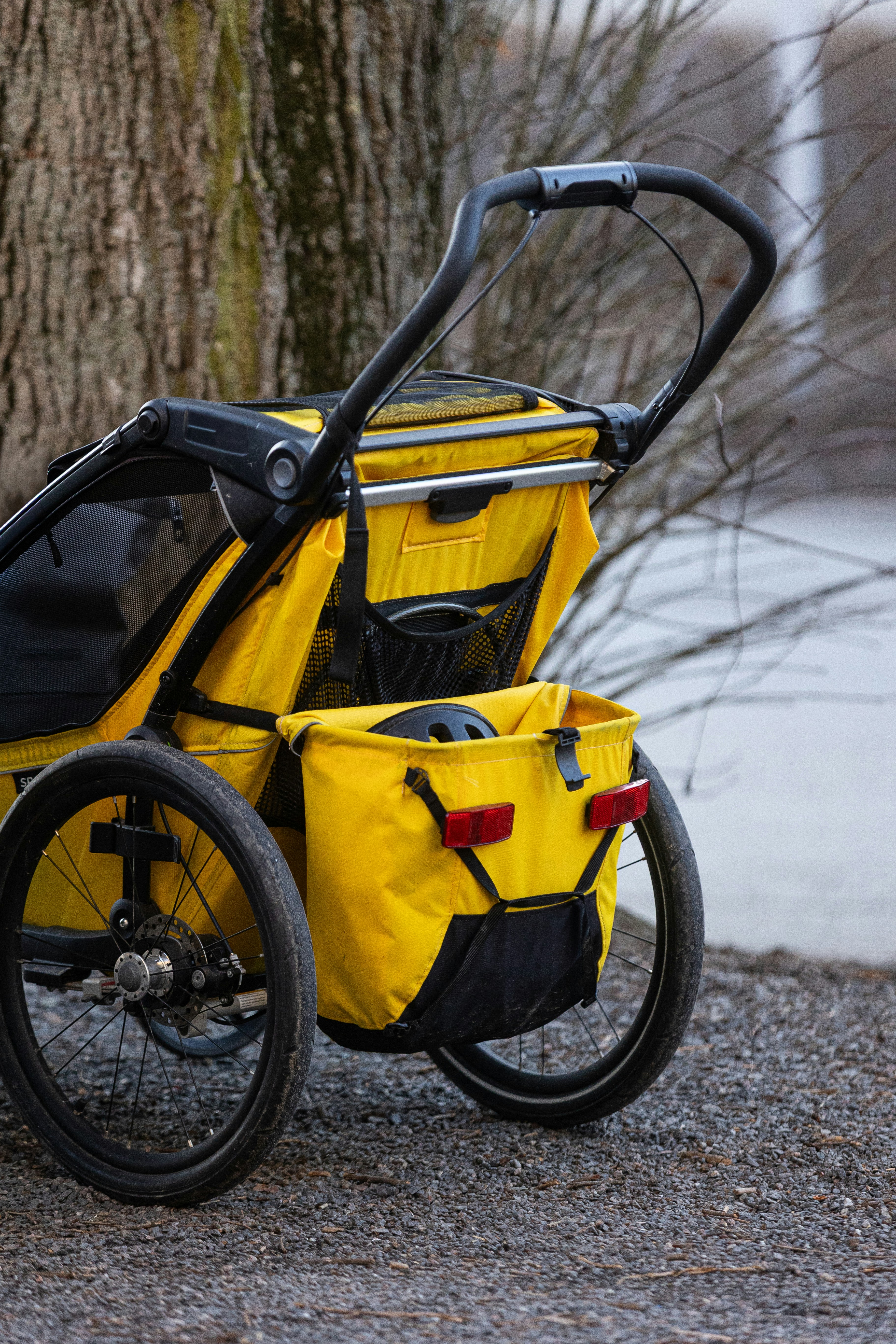 A yellow stroller parked next to a tree