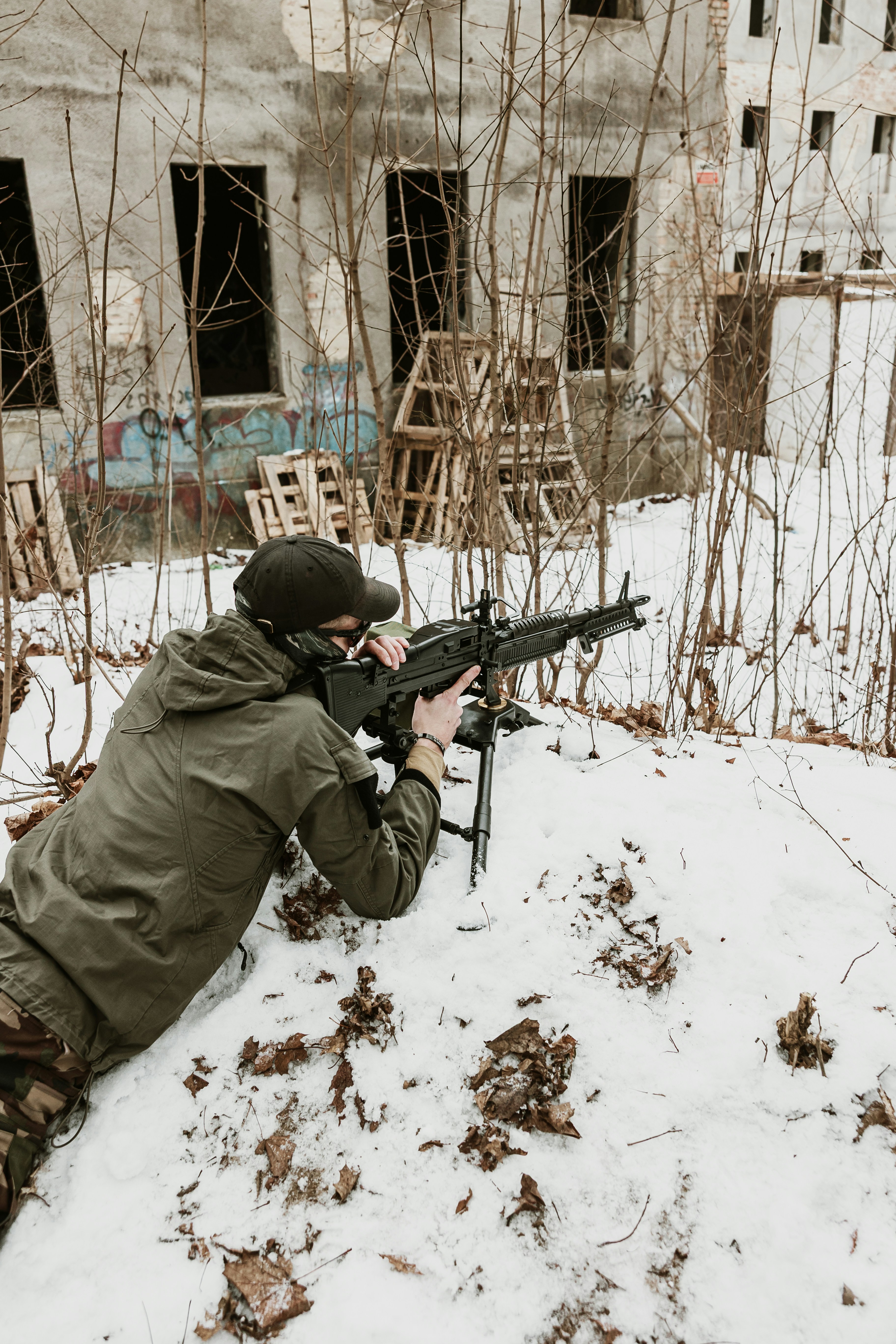 Soldat zielt mit Maschinengewehr in verschneiten Stadtruinen.