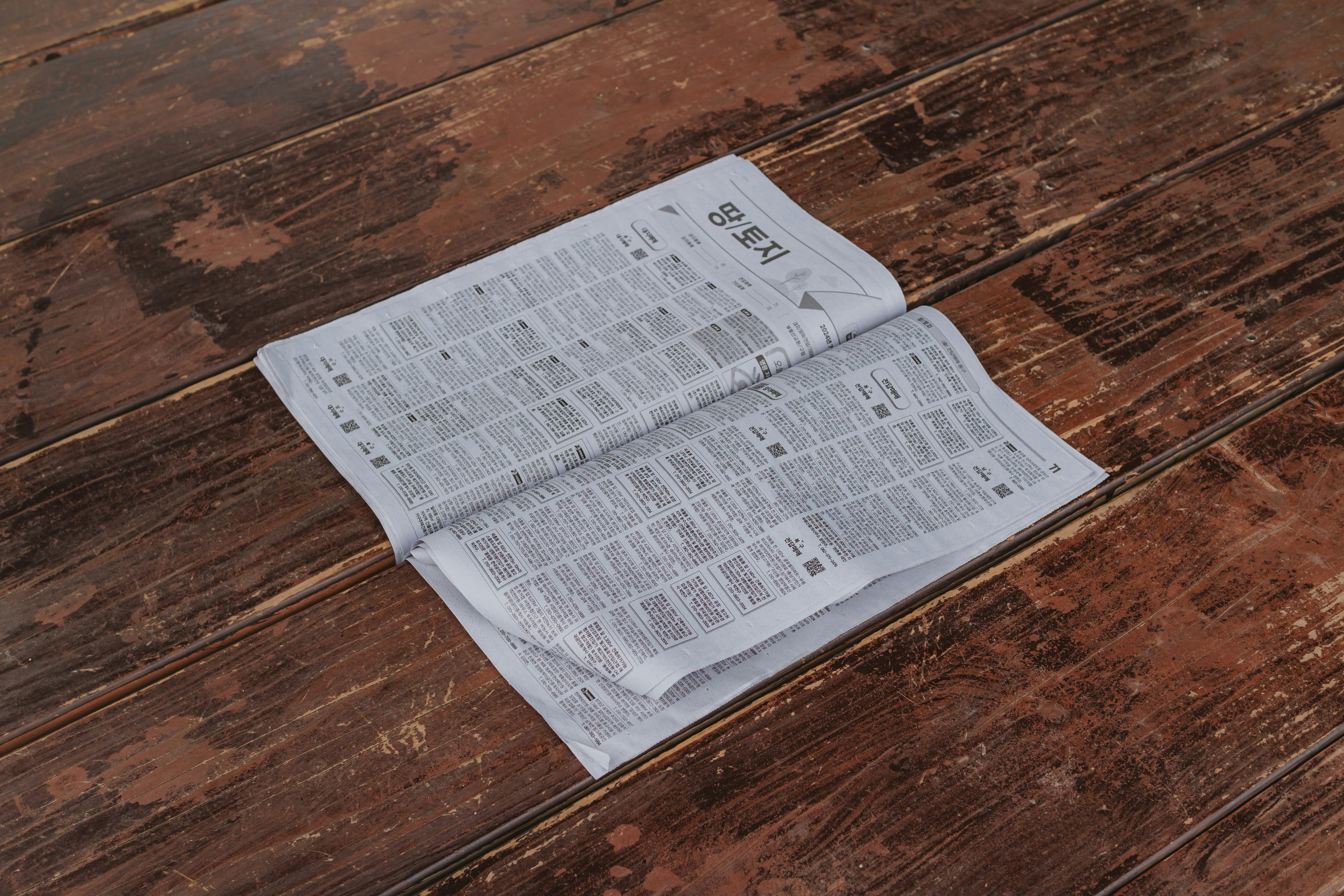 Open newspaper lying on a rustic wooden floor