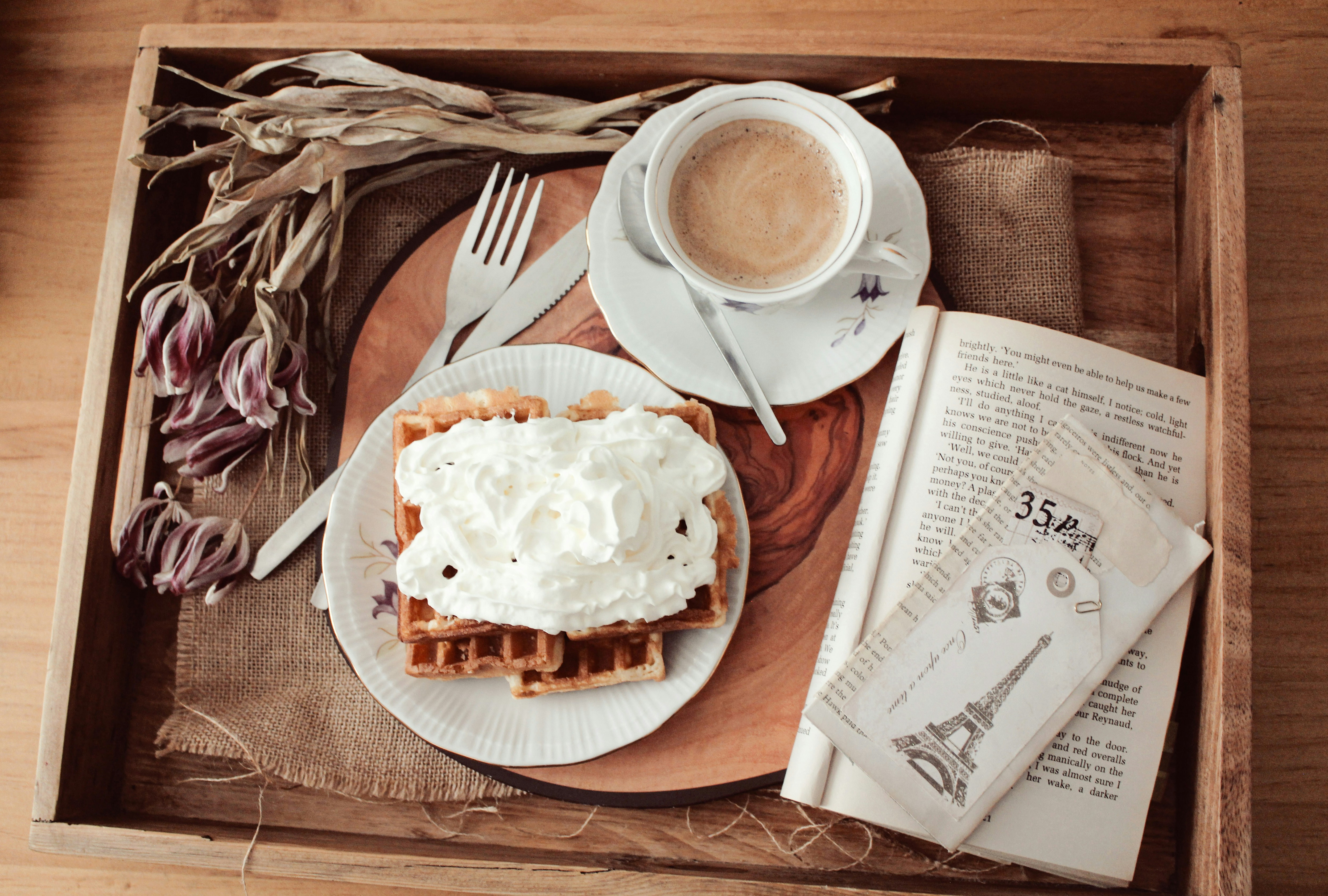 Waffles with whipped cream and coffee on a tray.