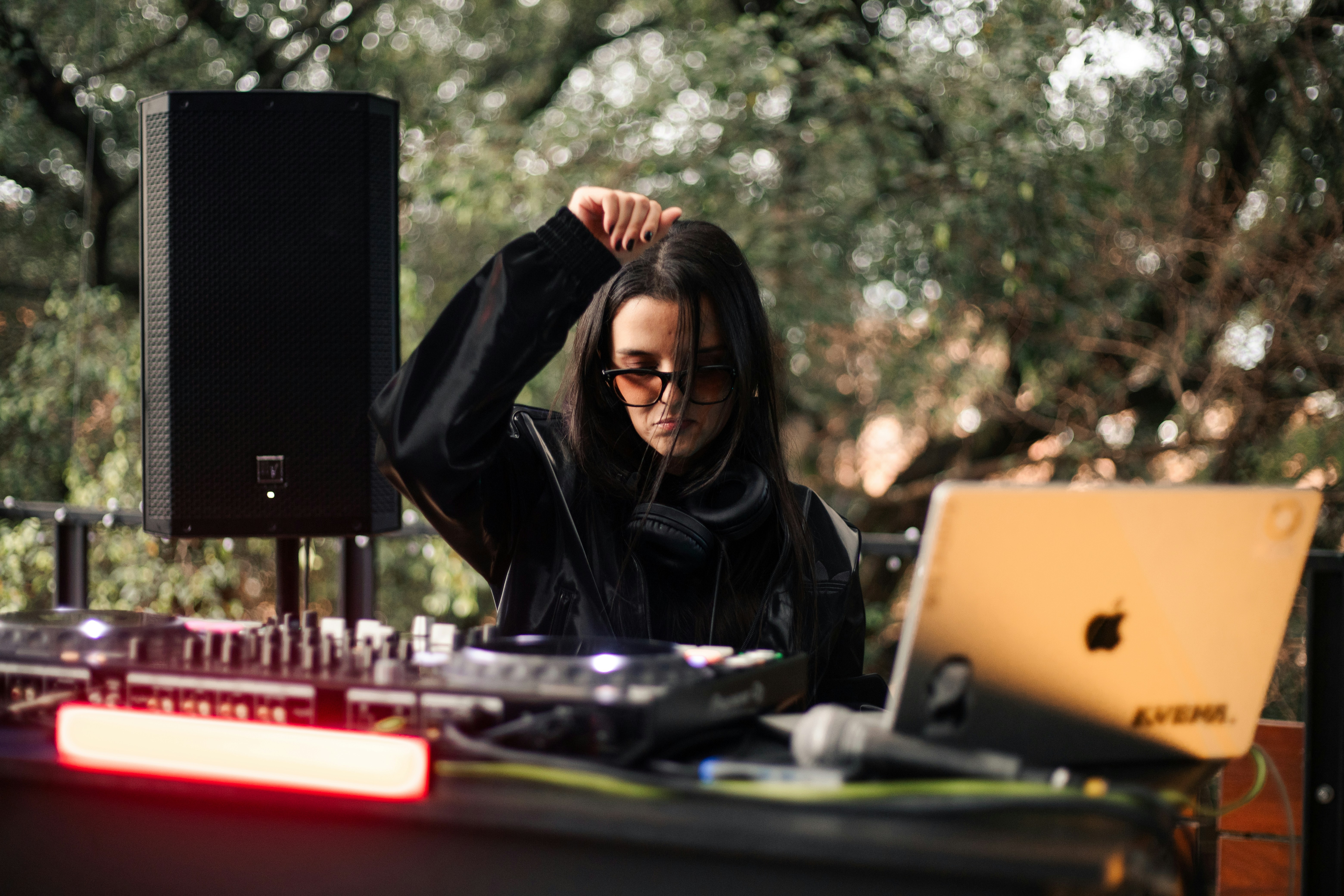 A dj in sunglasses plays music outdoors at night.