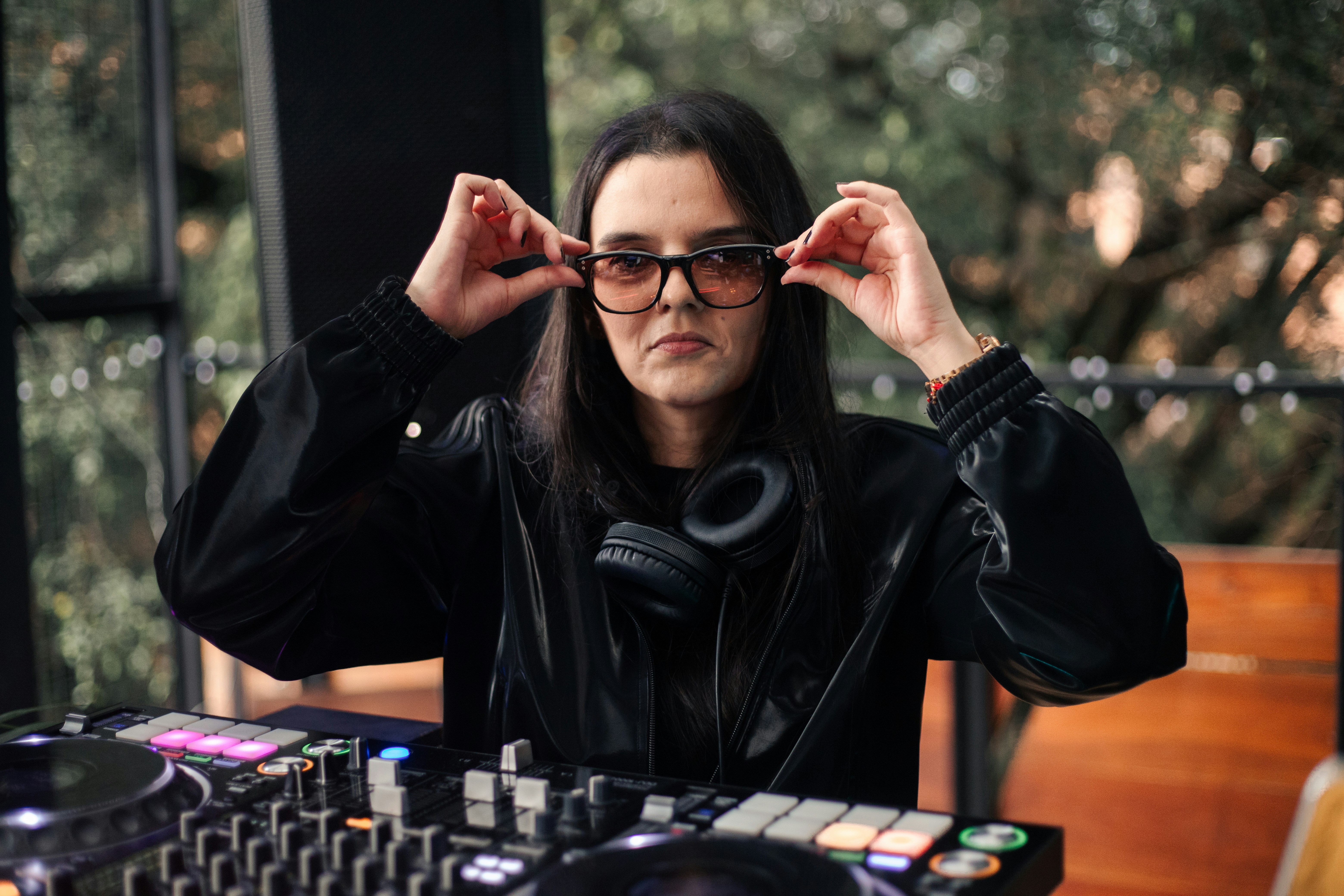 Dj adjusting sunglasses at turntables with headphones
