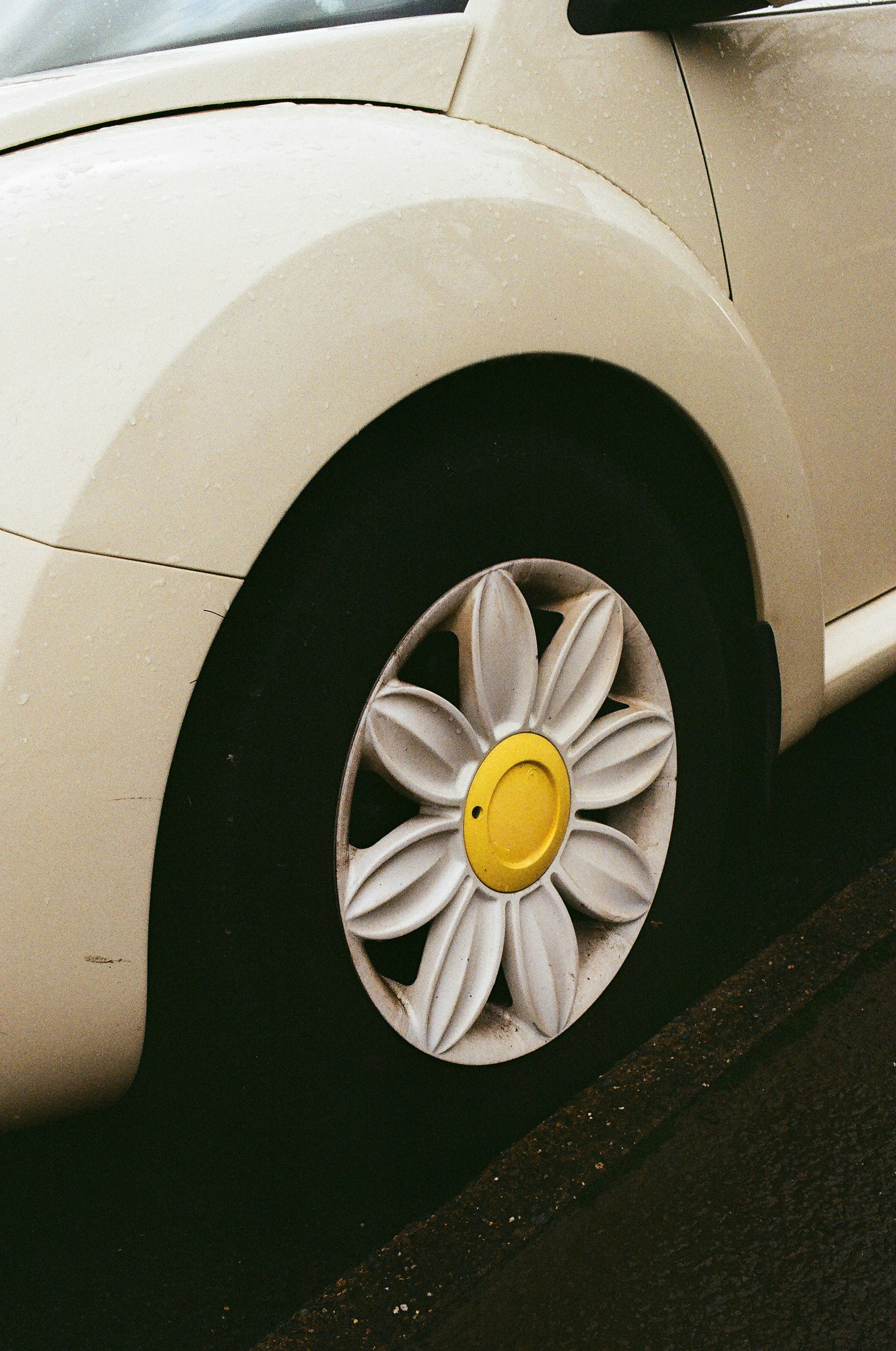 White car wheel with a yellow daisy hubcap