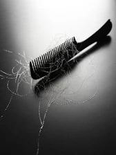 A black comb with strands of hair on it