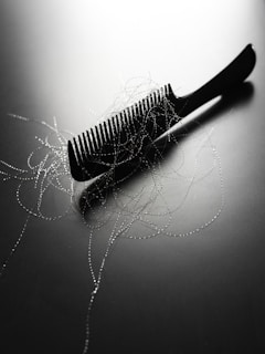A black comb with strands of hair on it.
