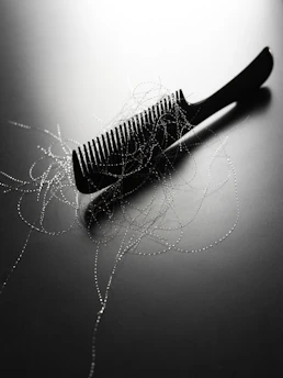 A black comb with strands of hair on it