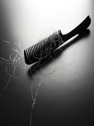 A black comb with strands of hair on it.