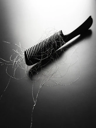 A black comb with strands of hair on it.