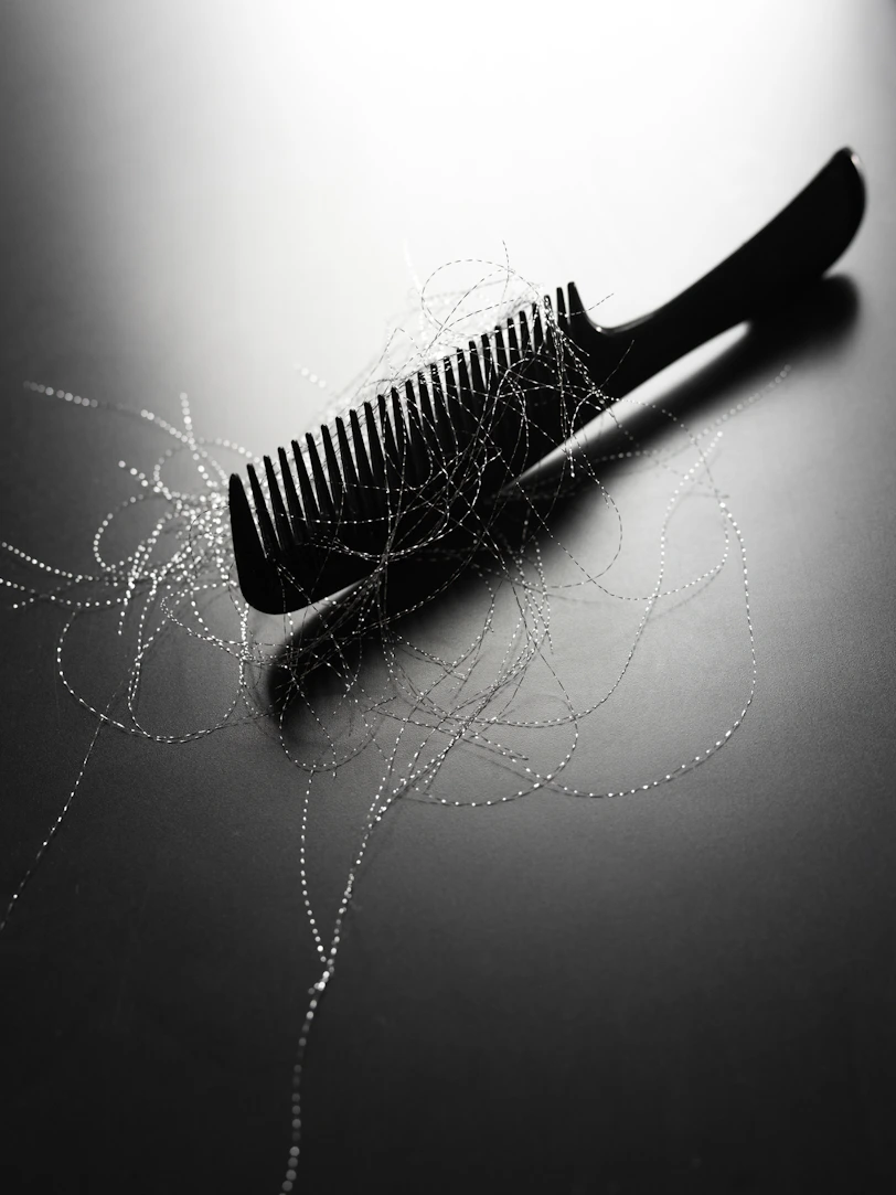 A black comb with strands of hair on it.