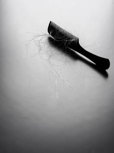 A black comb with loose strands of hair.