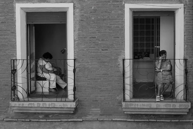 Two women on balconies, one holding a baby.