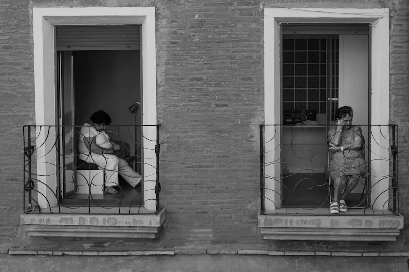 Two women on balconies, one holding a baby.