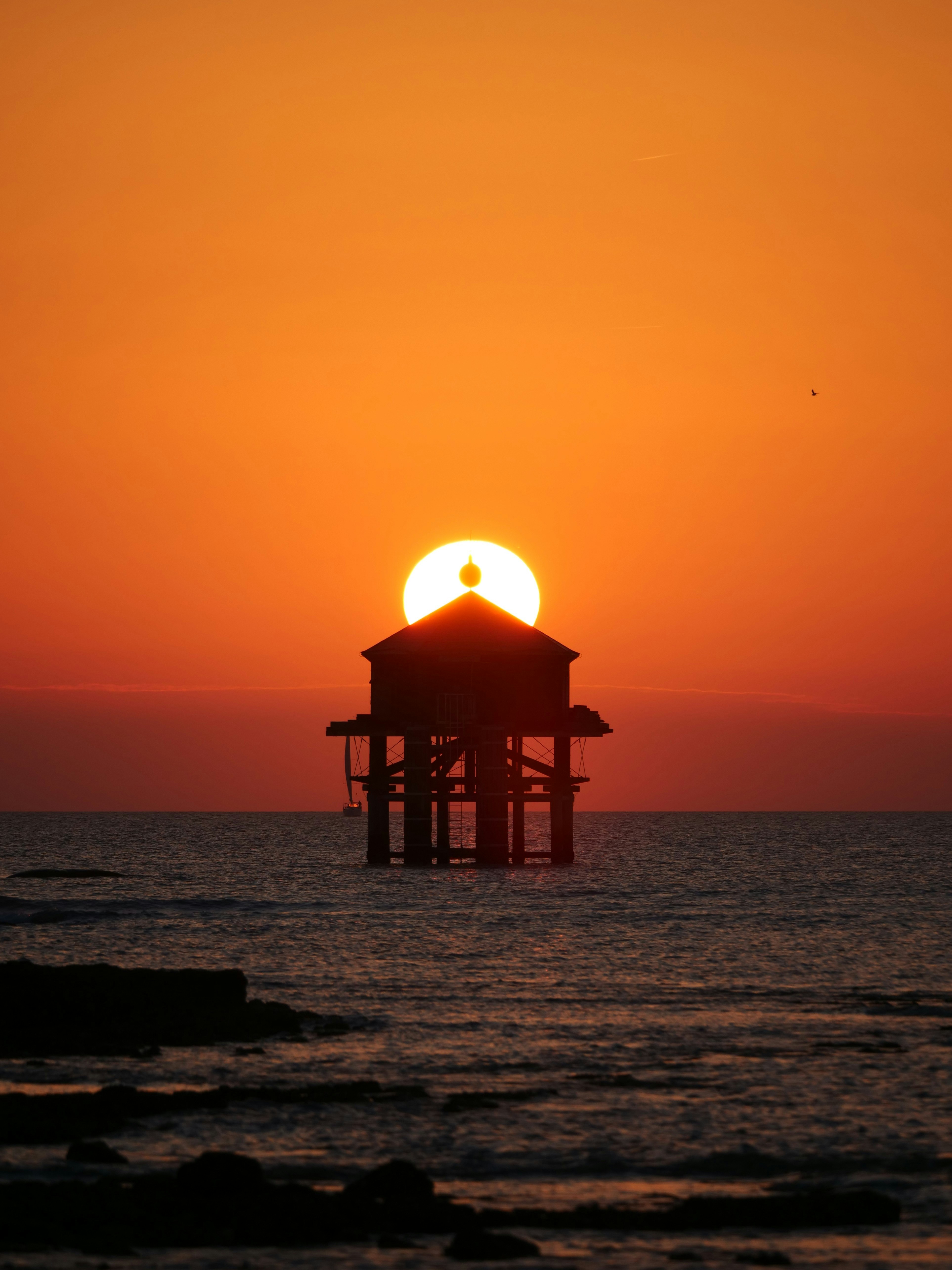 Small house on stilts in the ocean at sunset