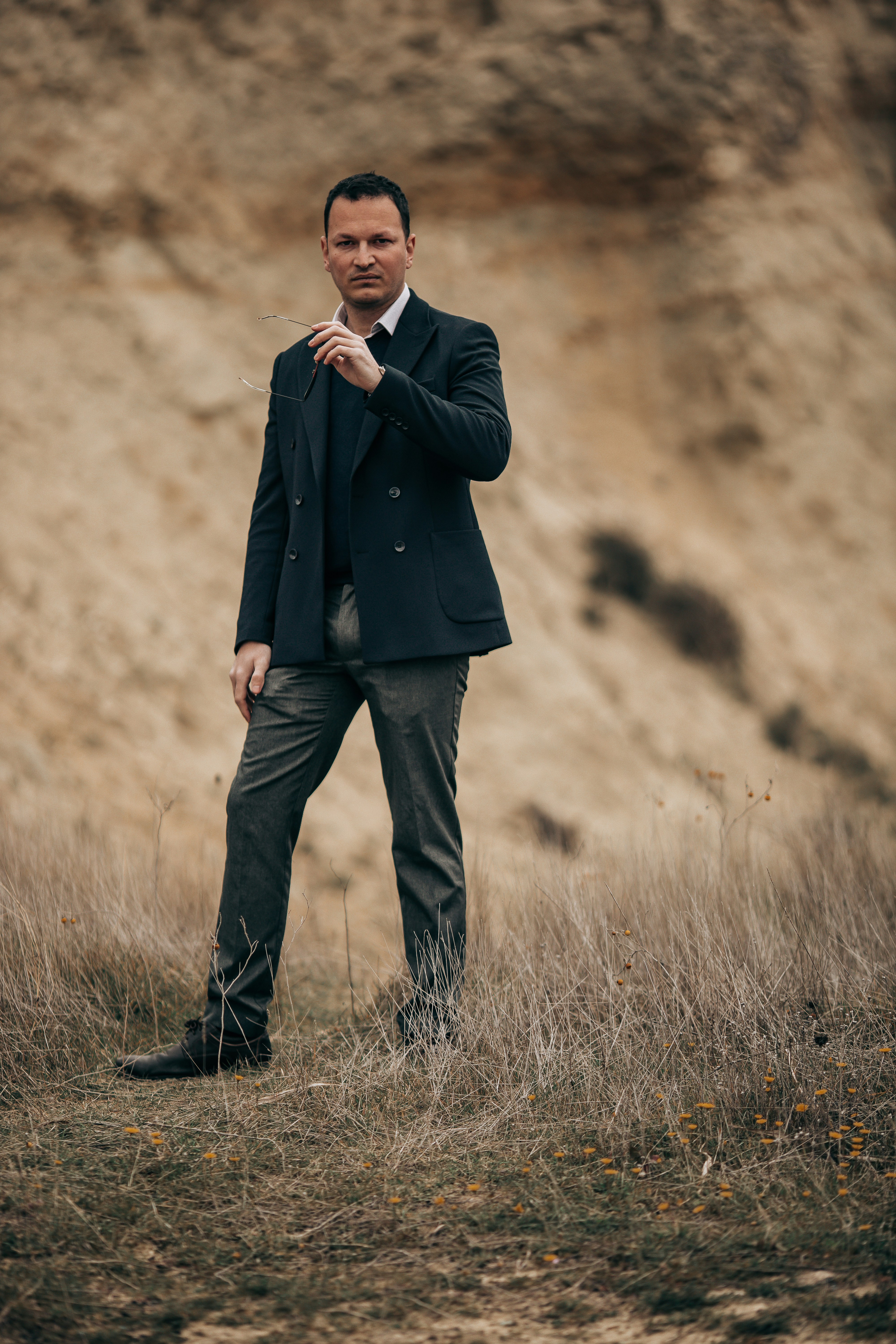 Mann im Anzug, der eine Brille in einer trockenen Landschaft hält