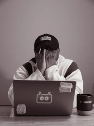 Person with hands over face at laptop