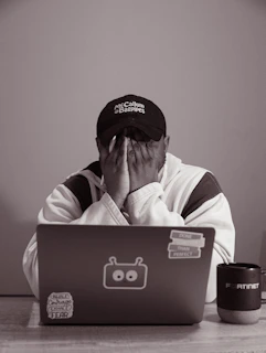 Person with hands over face at laptop