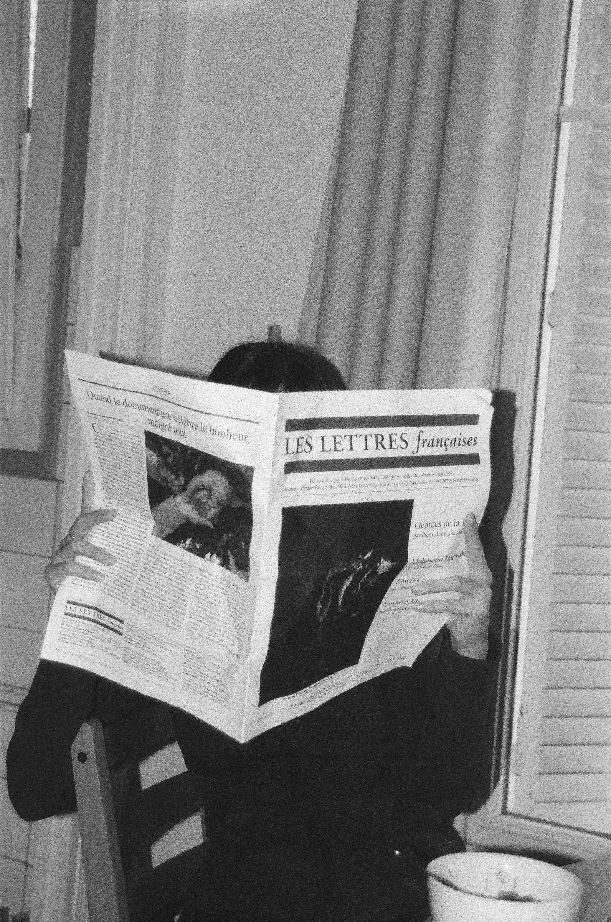 Person reading a newspaper at a table.