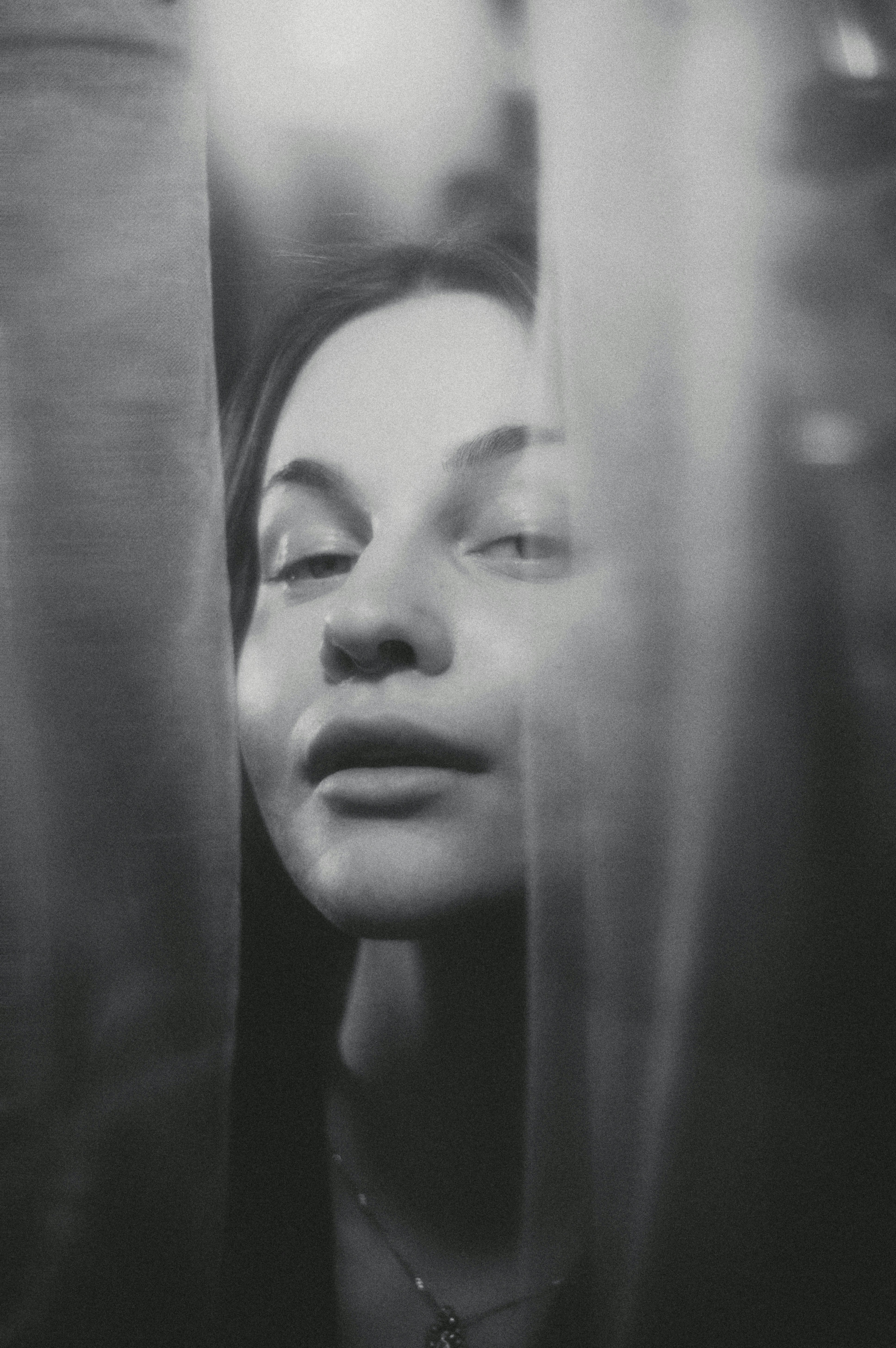 Une femme jette un coup d’œil à travers des rideaux transparents