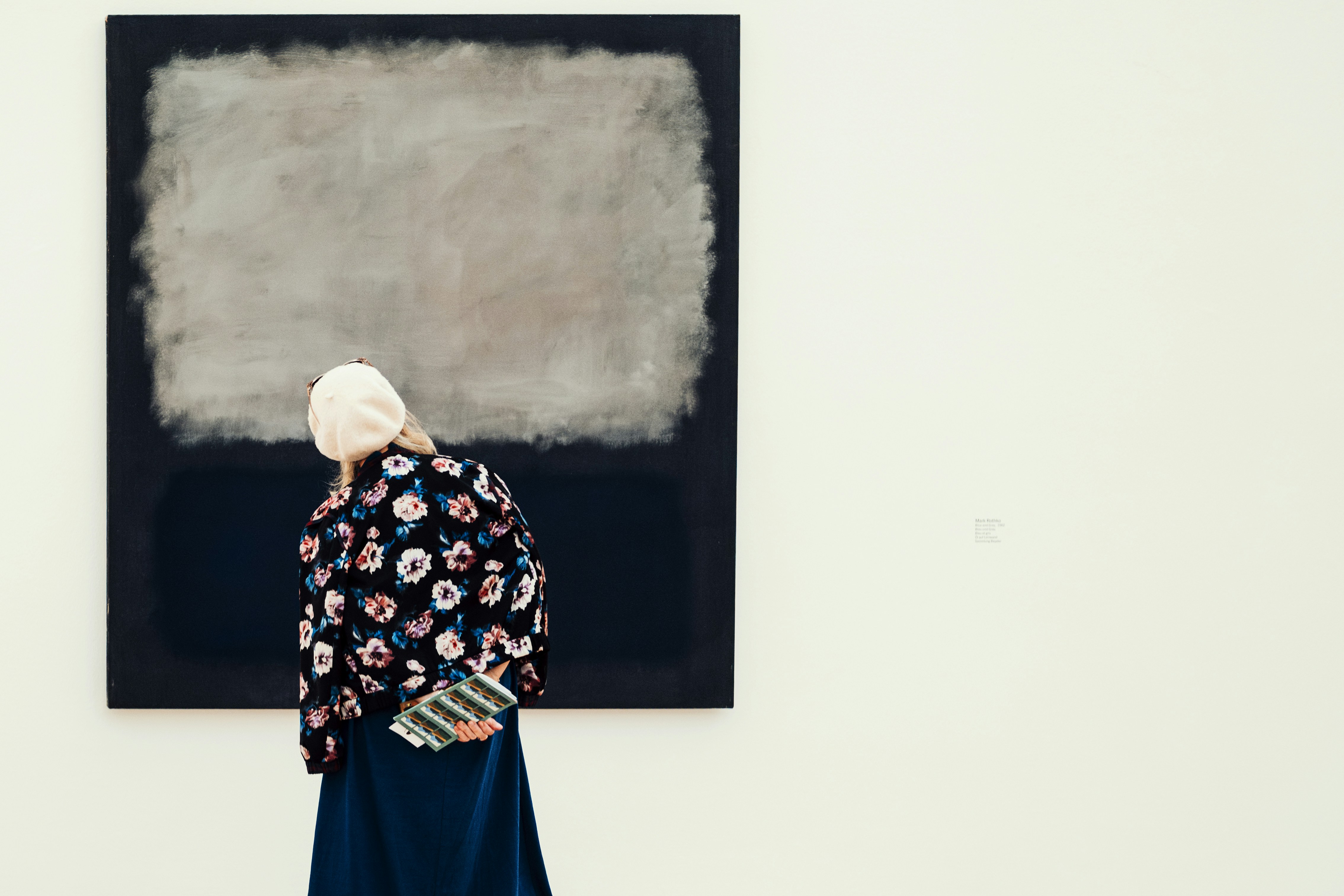 Femme observant une grande peinture abstraite dans une galerie