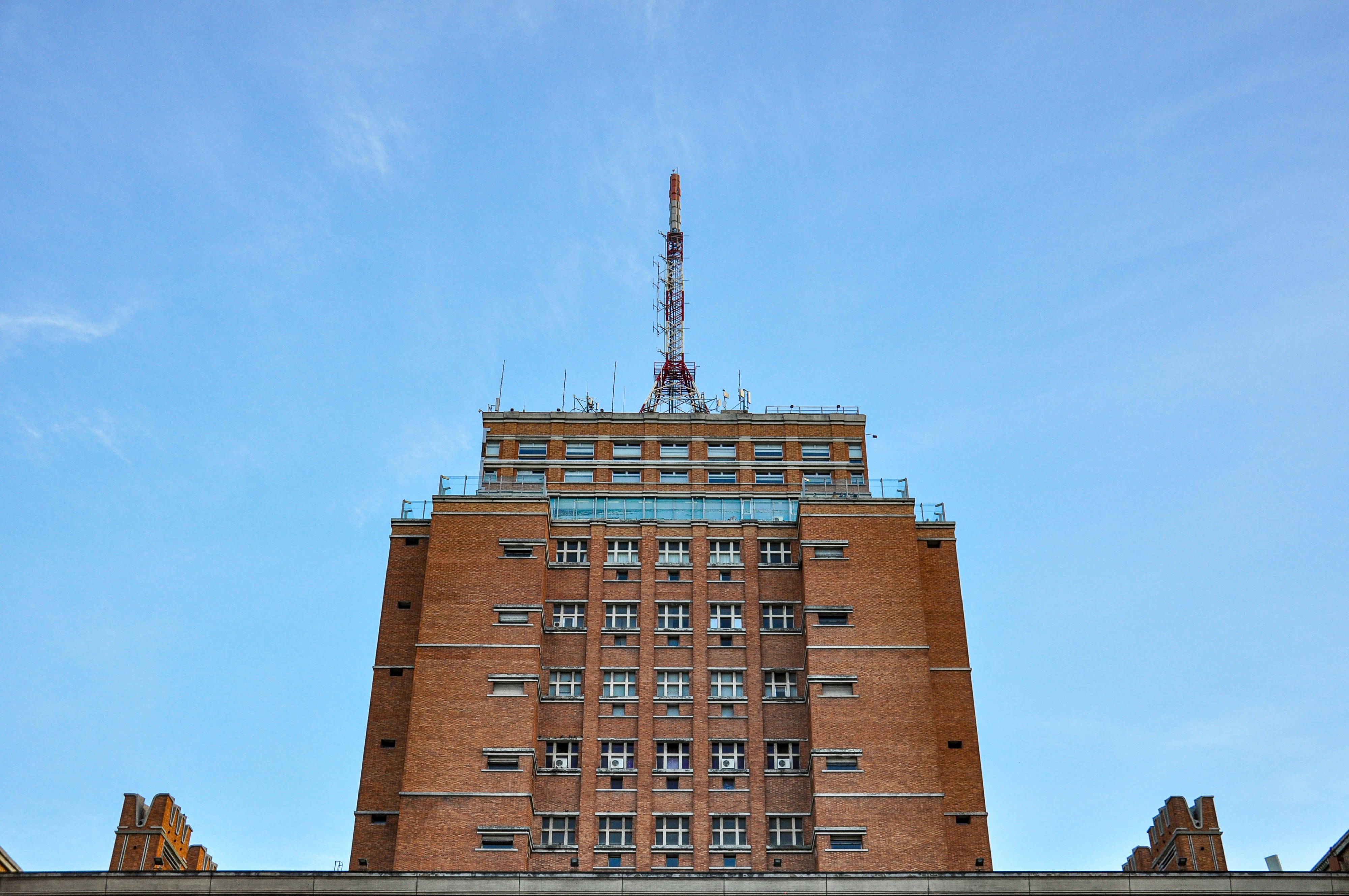 Tall brick building with antenna against blue sky