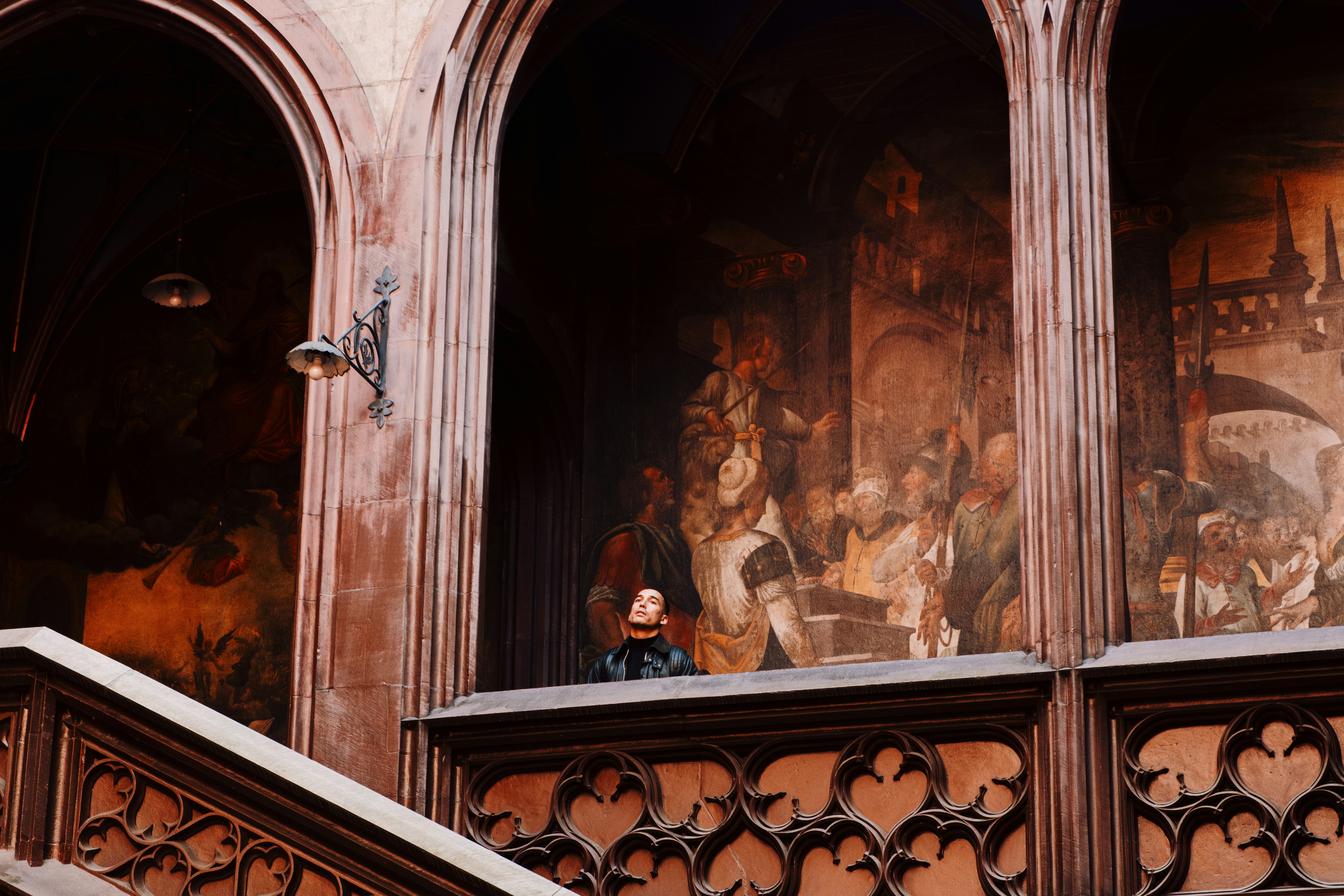 Femme regardant depuis un balcon avec des fresques