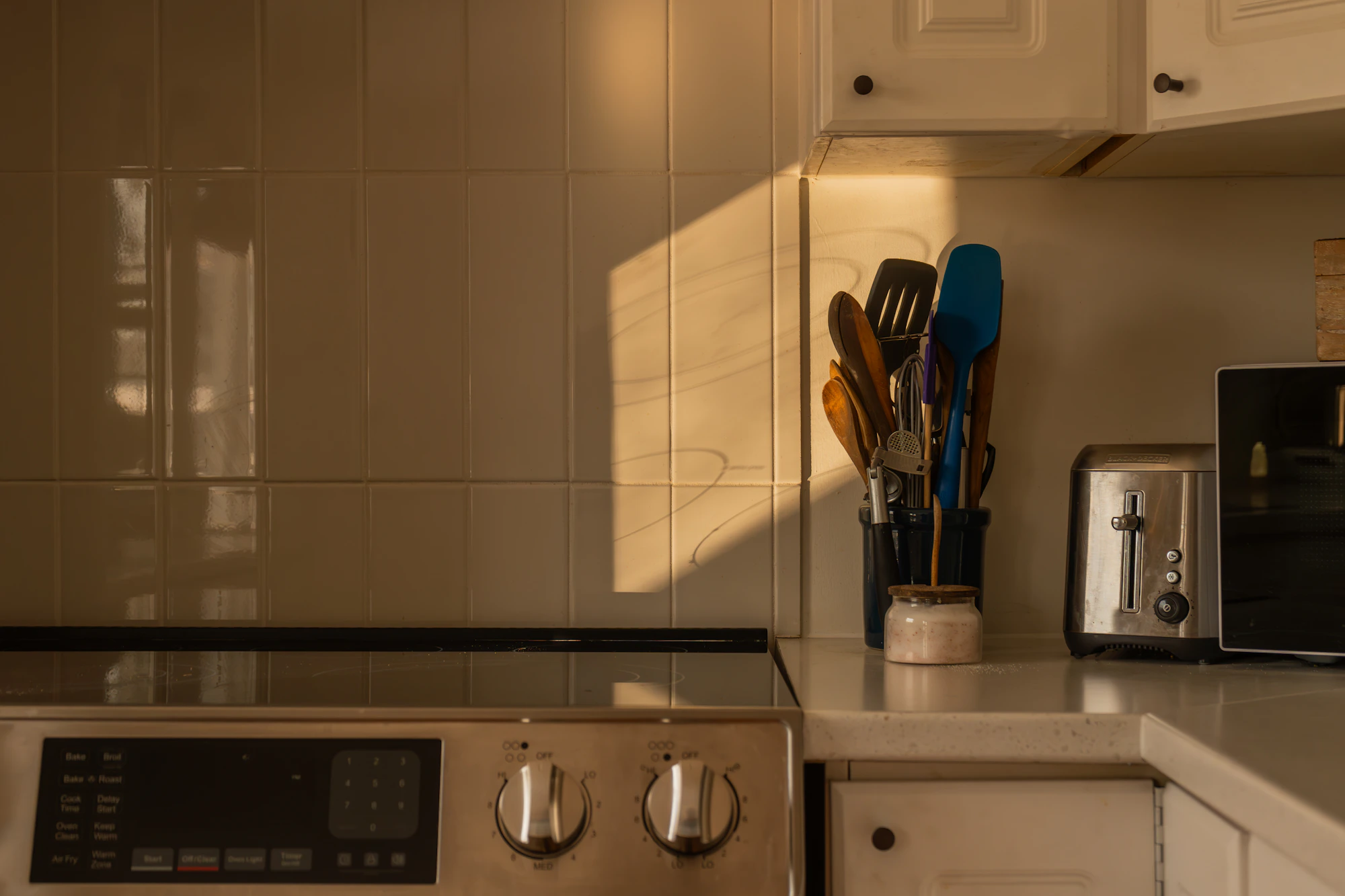 Warm modern kitchen counter with a toaster and everyday cooking utensils