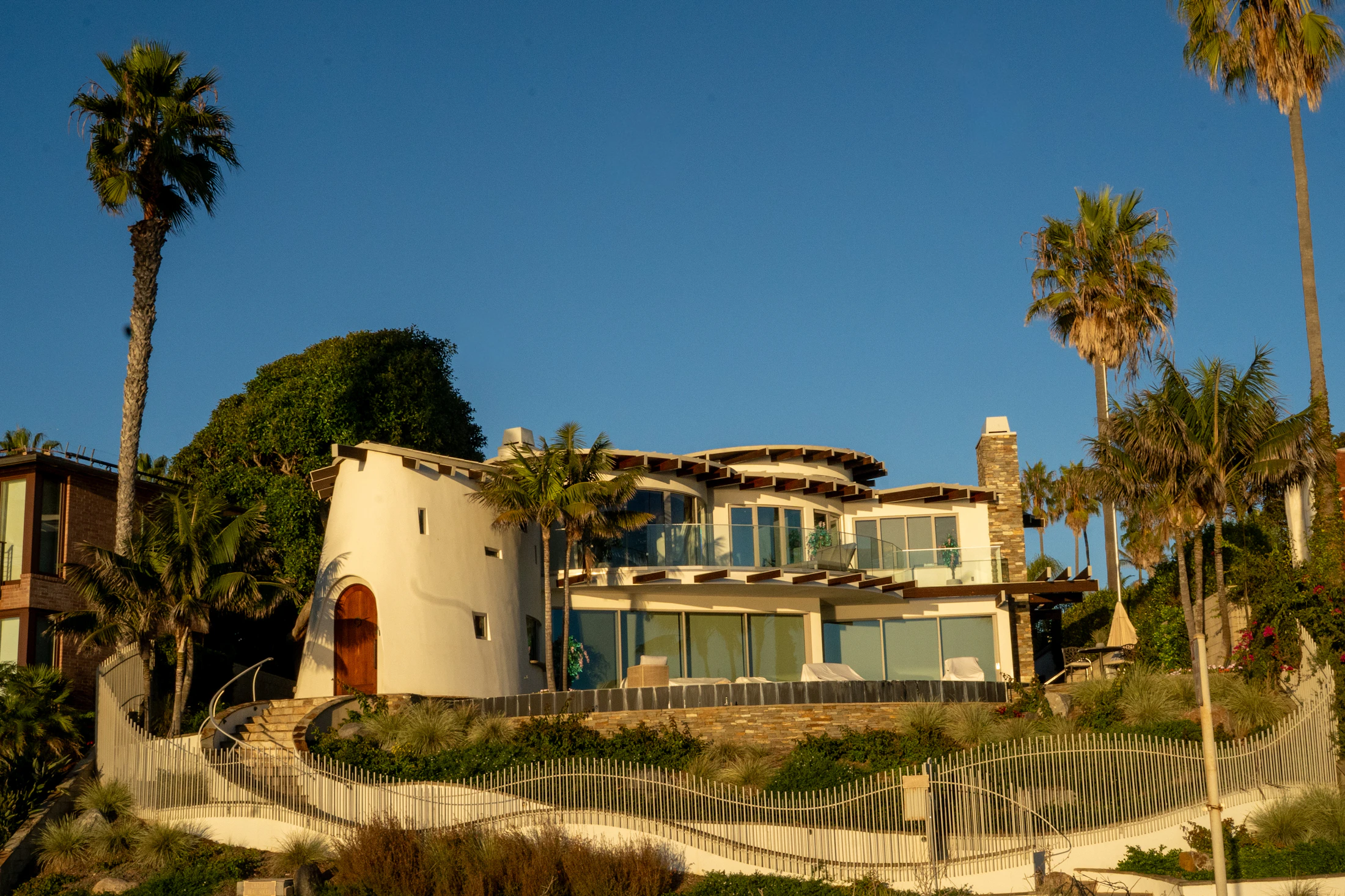 Luxury coastal contemporary home with a curved tower and palm trees in San Diego