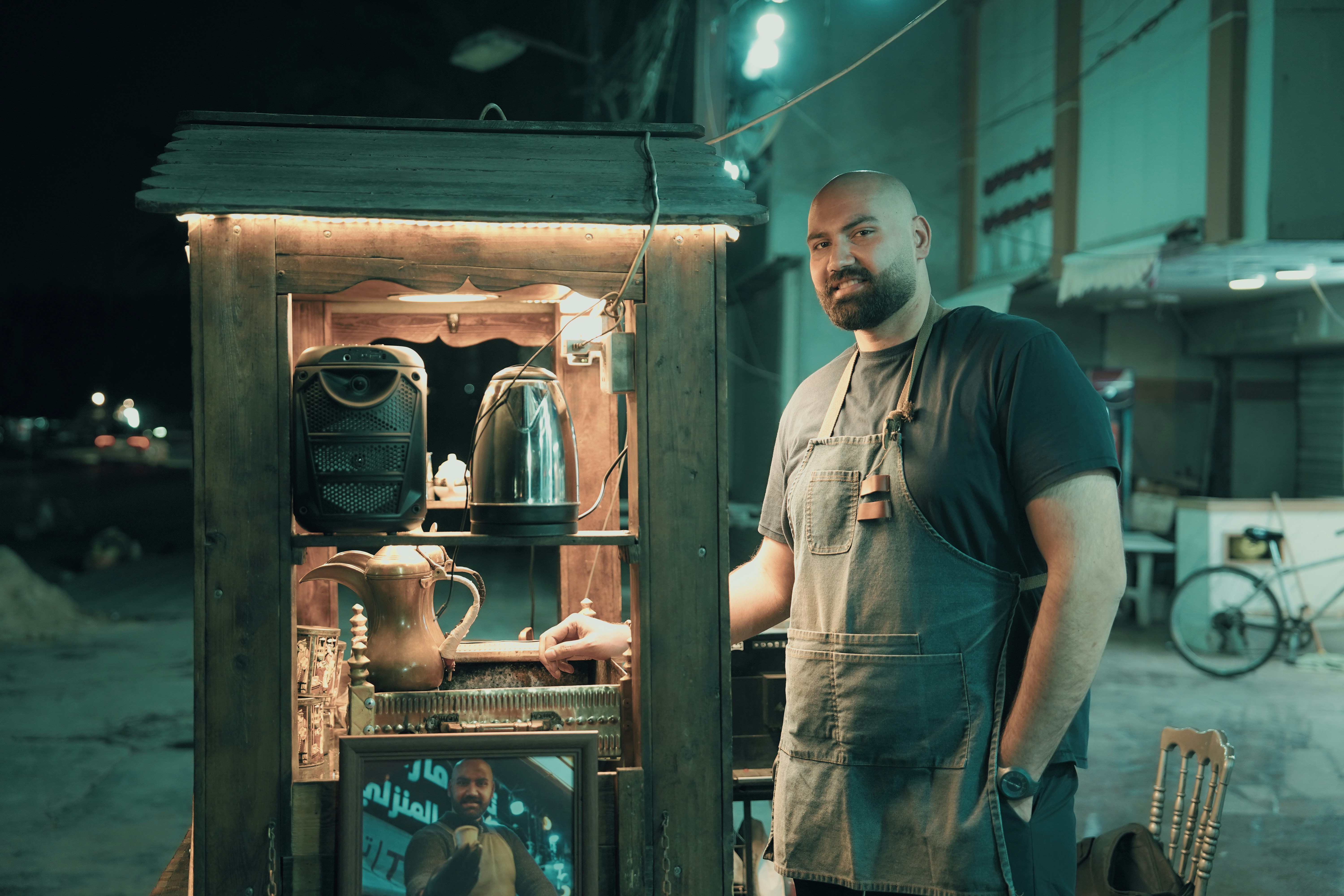 Man standing by a street food cart at night.