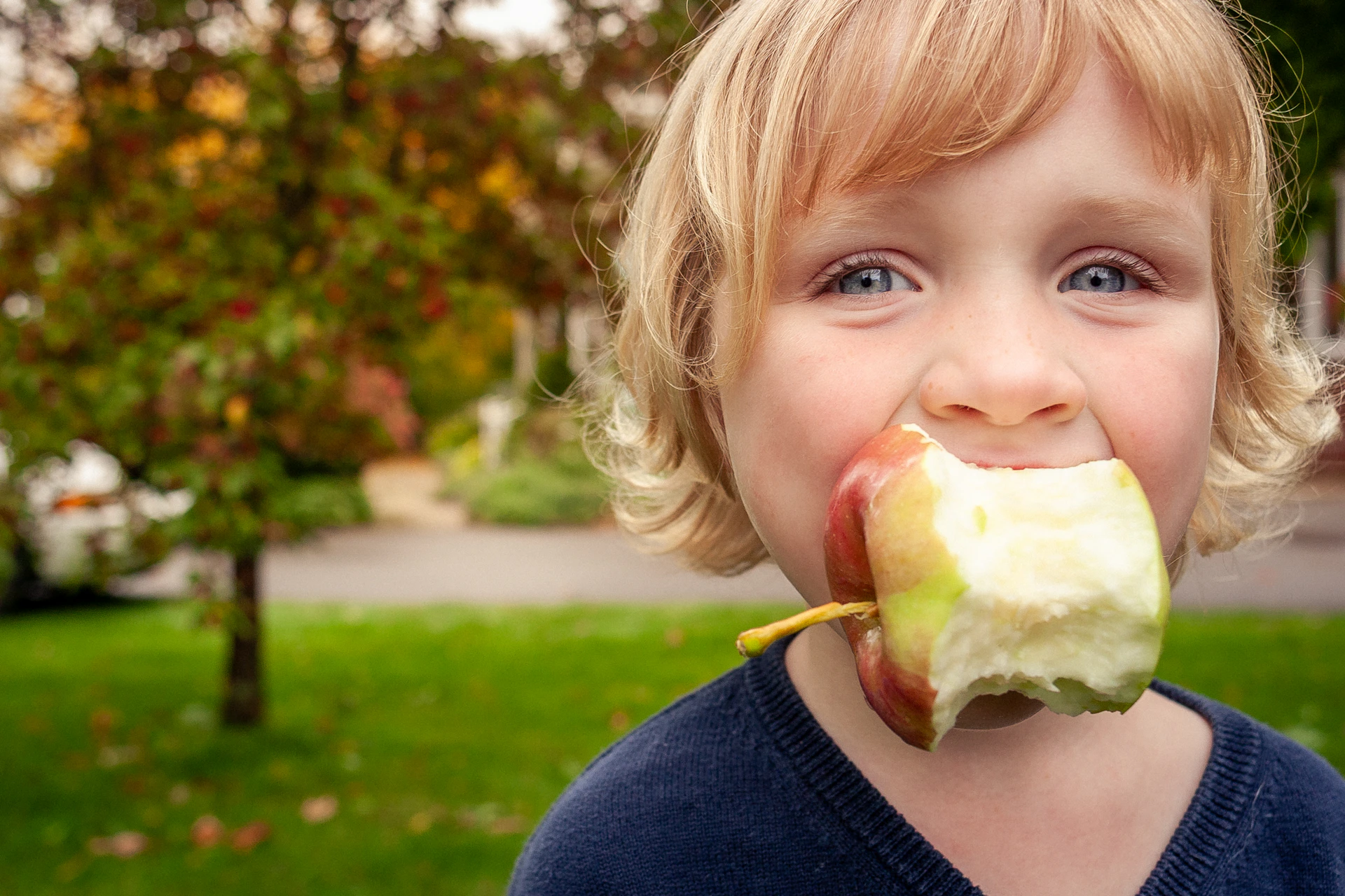 Young child with a bitten apple in mouth