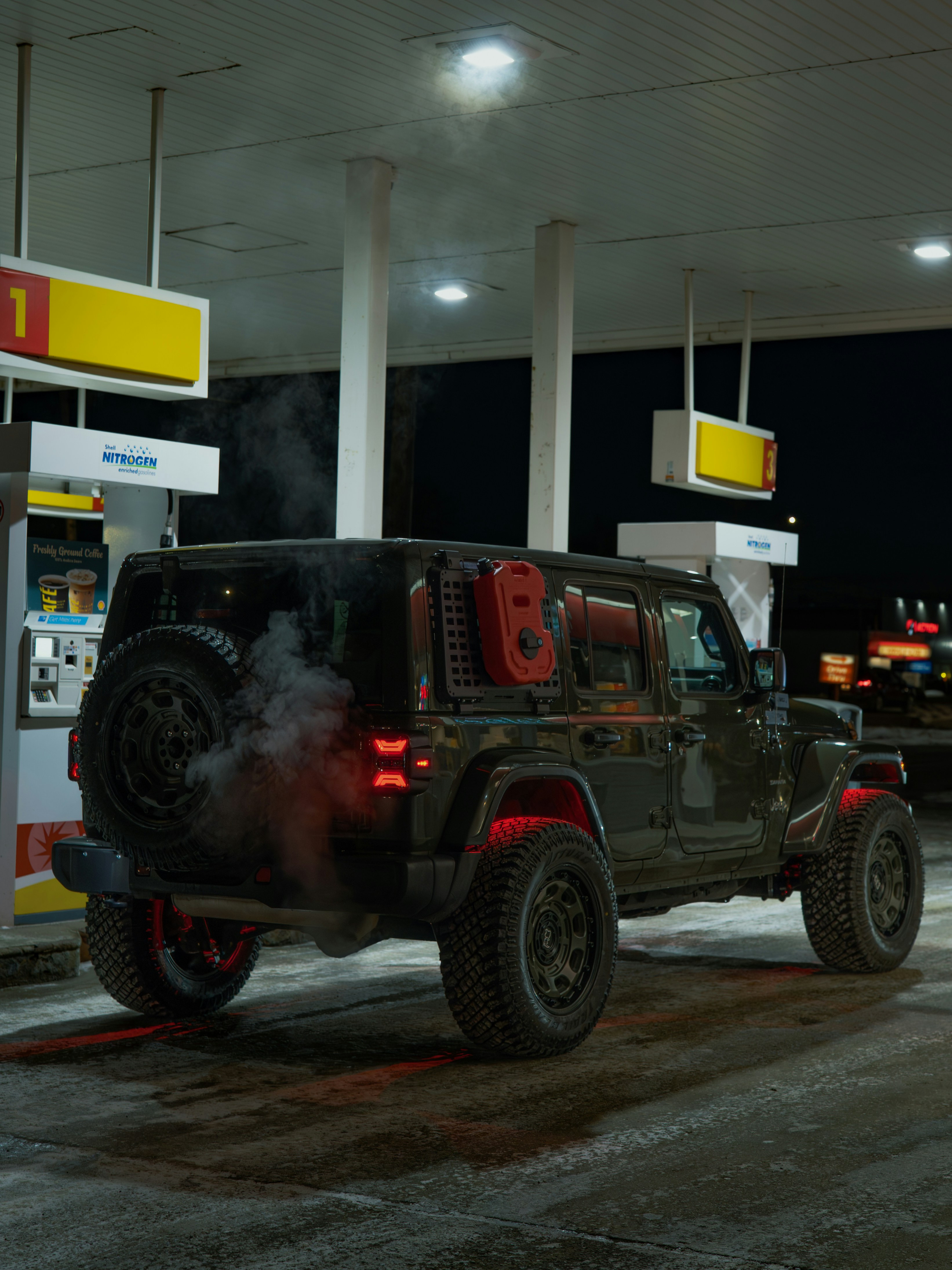 Dark jeep wrangler at a gas station at night