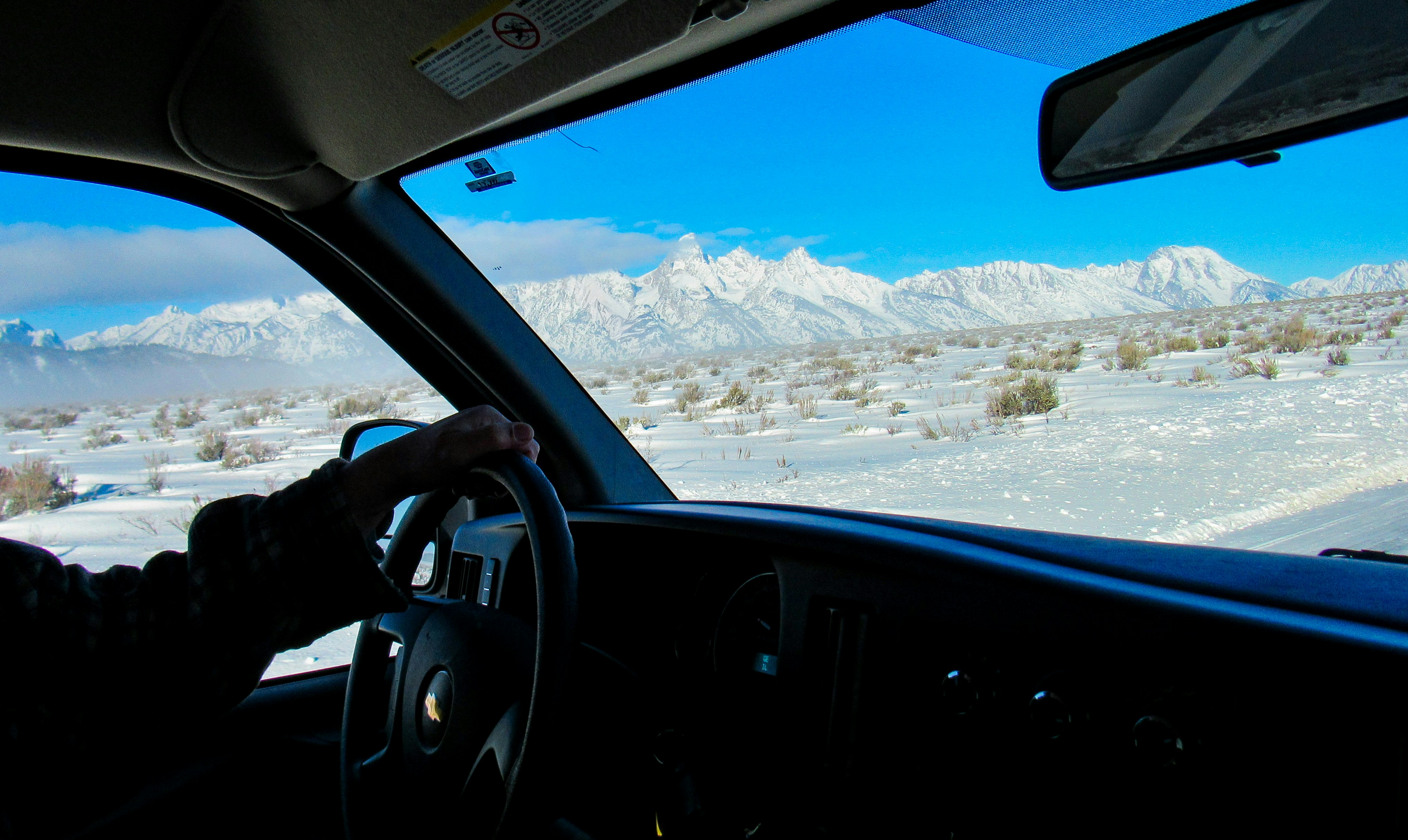 Driving through a snowy landscape towards mountains.