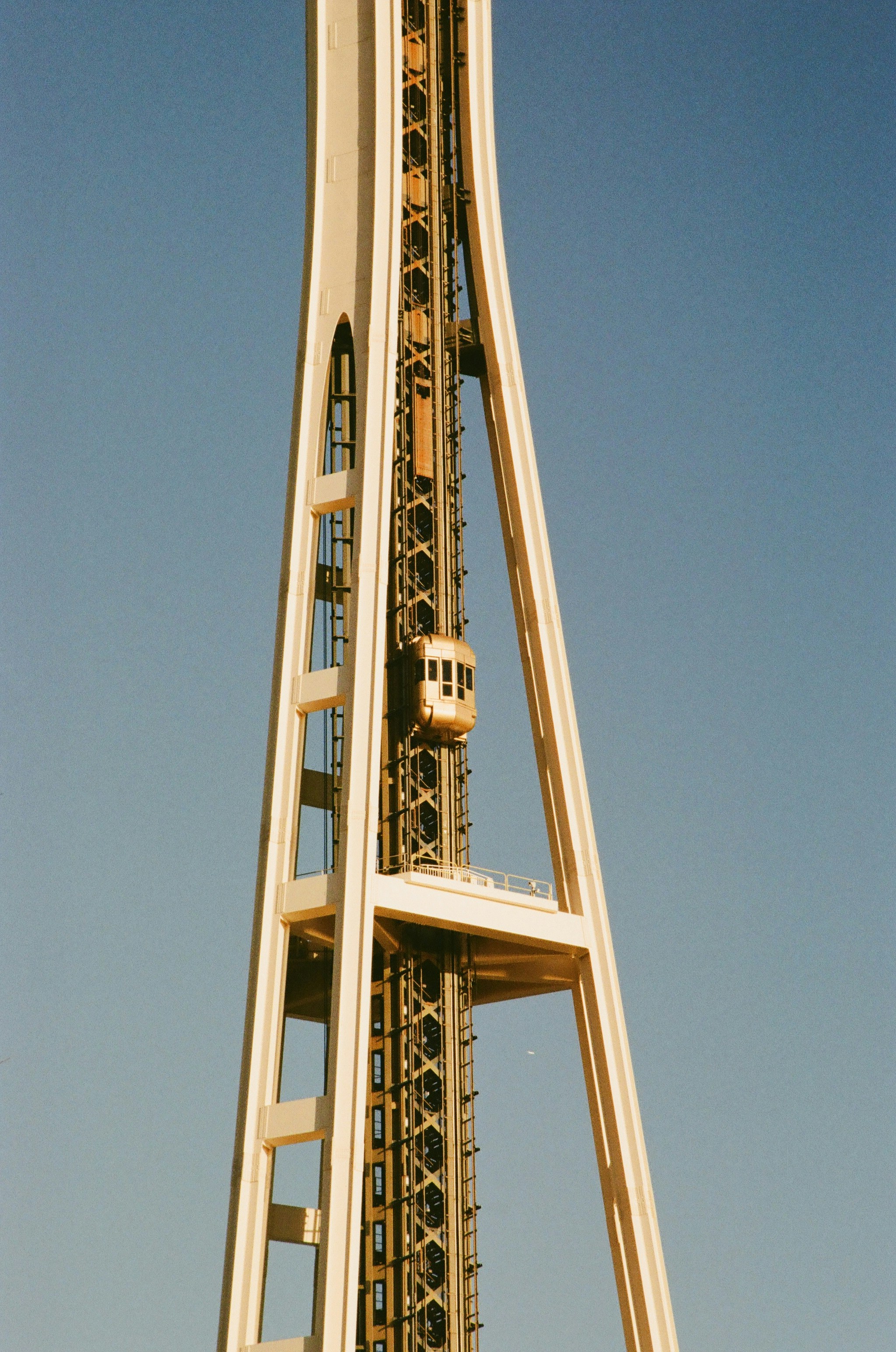 An elevator ascends a tall, modern tower structure.