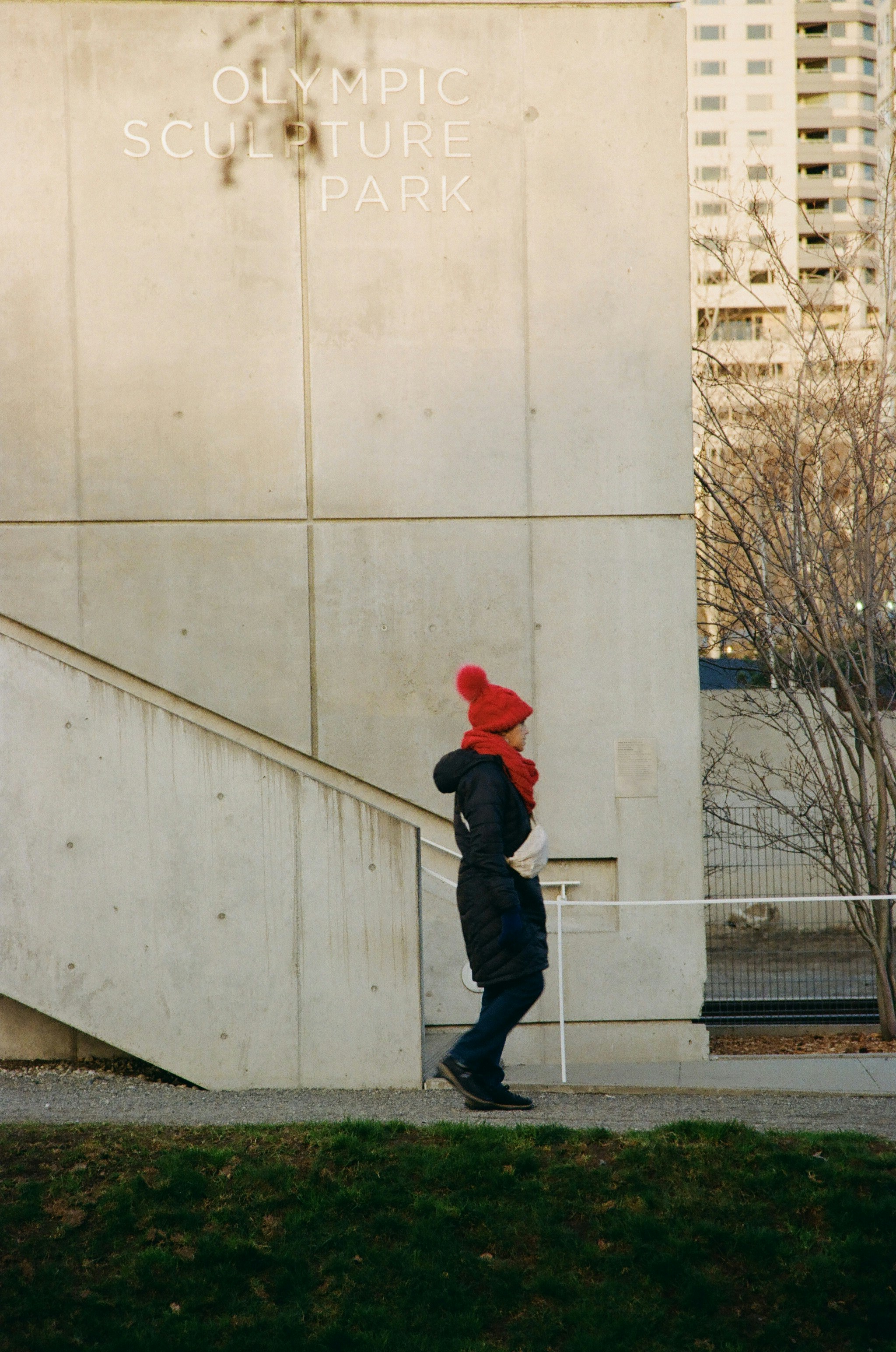 Donna con il cappello rosso passa vicino all'edificio del parco di sculture olimpica
