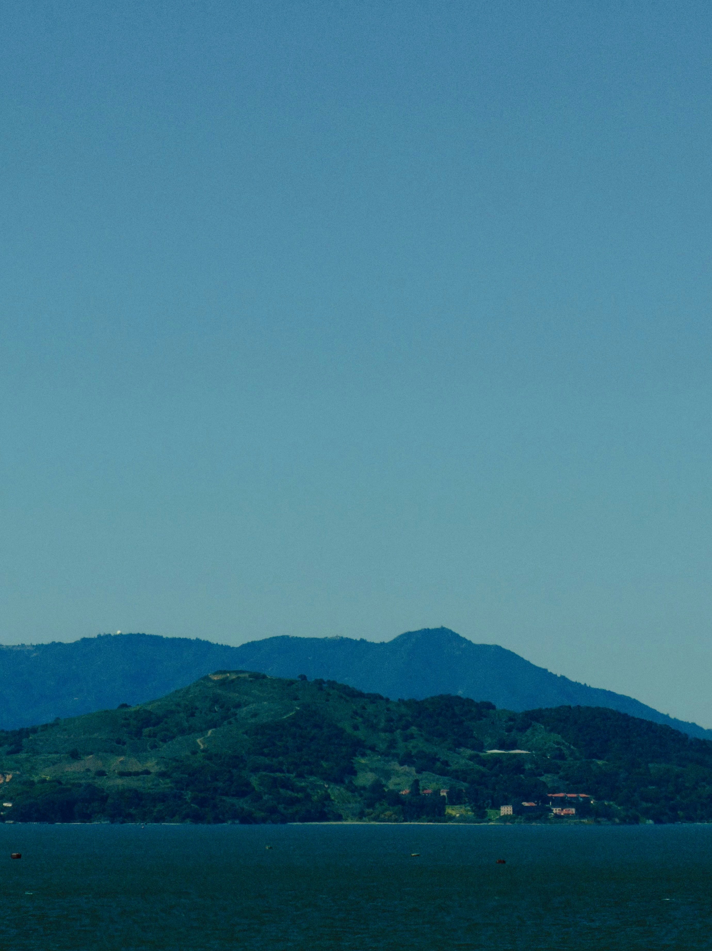 Green hills and mountains under a clear blue sky.
