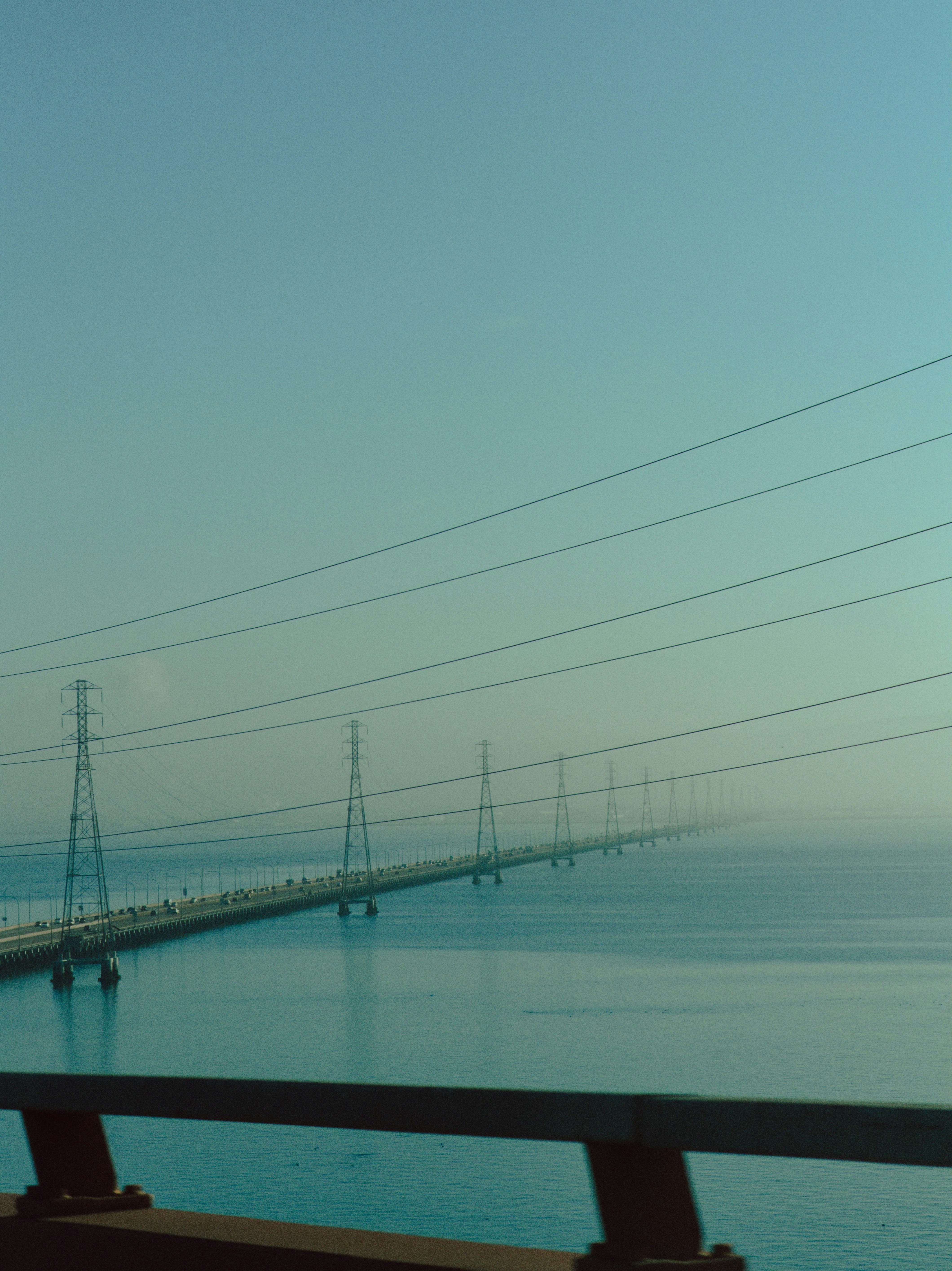 Long bridge over calm blue water with power lines