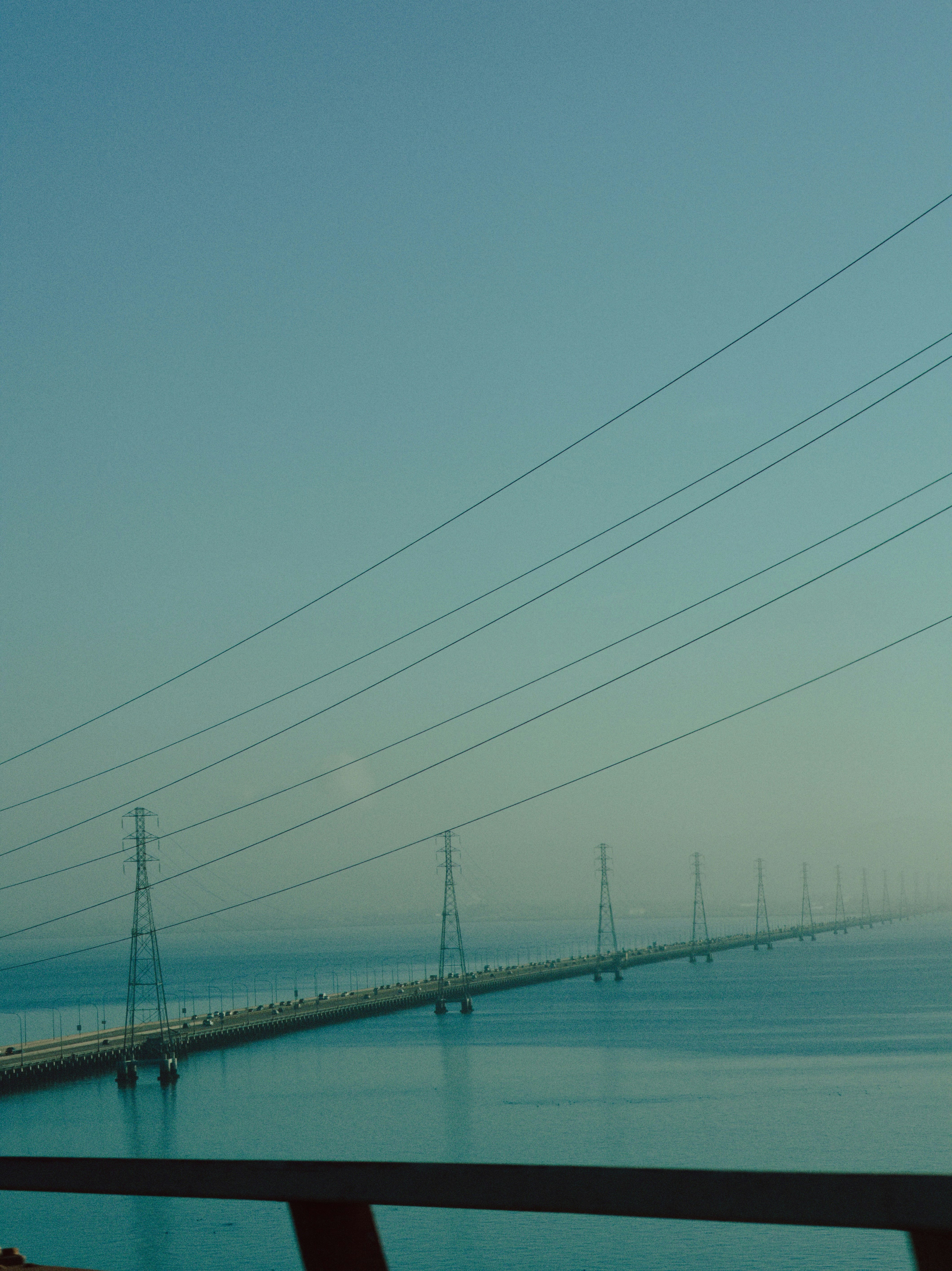 Long bridge with power lines over calm water